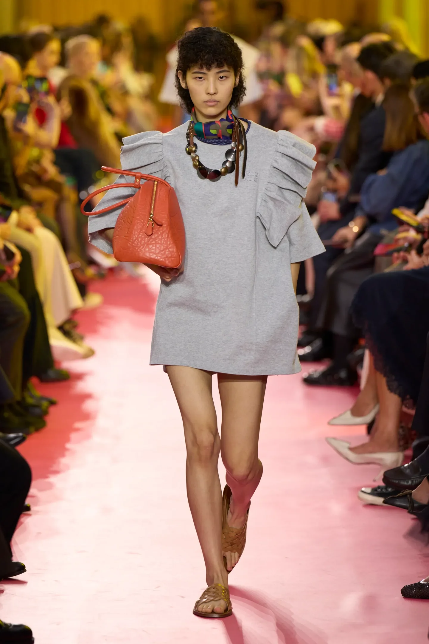 A moda anos 2010 é marcada por um mix de estilos e influências. Nesta imagem, uma modelo apresenta um vestido cinza com mangas bufantes, refletindo a tendência oversized da época.