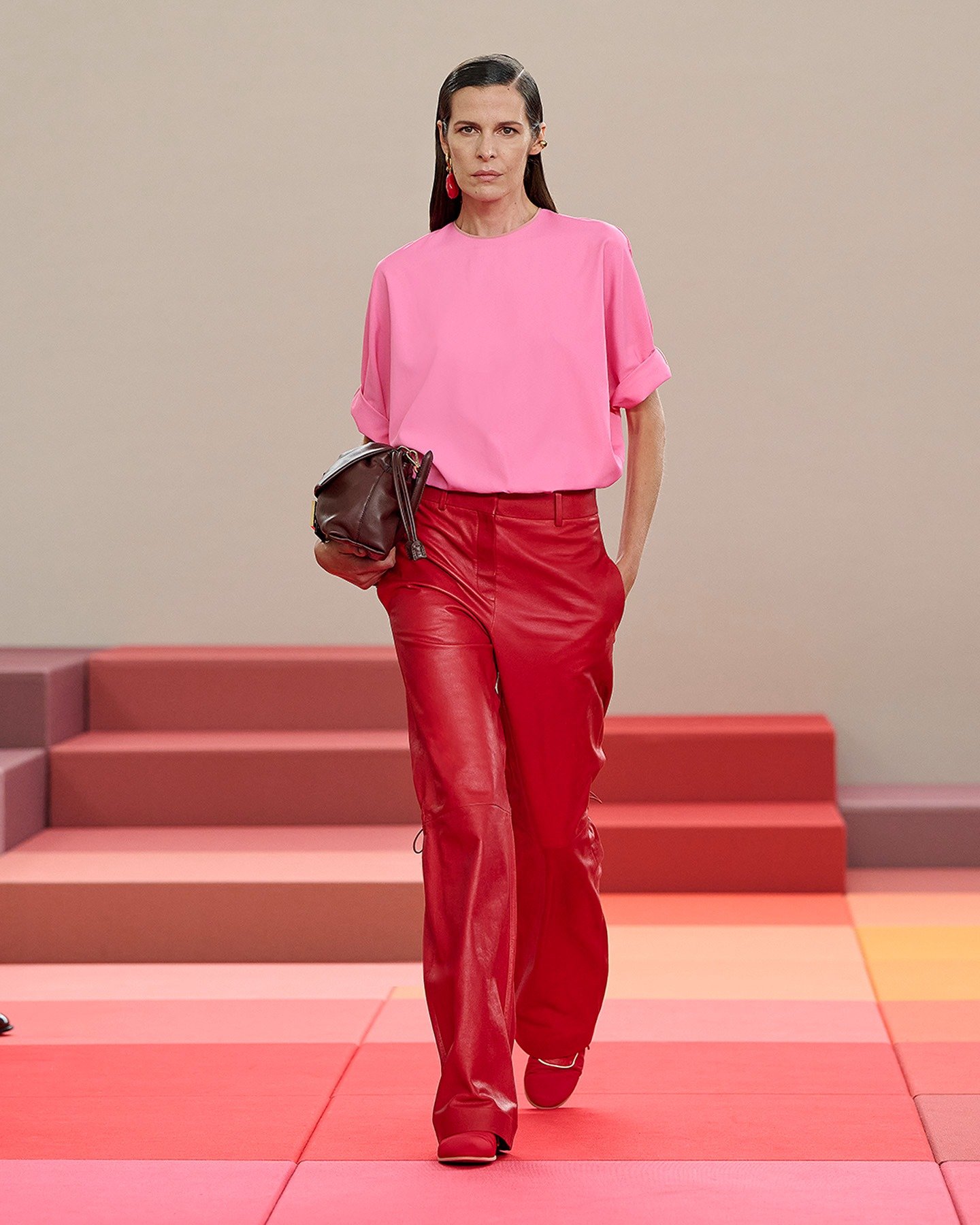 A moda anos 2010 é marcada por combinações ousadas e cores vibrantes, como neste look que destaca uma blusa rosa e calças vermelhas de couro. O contraste das cores é um elemento-chave, refletindo a audácia da época.