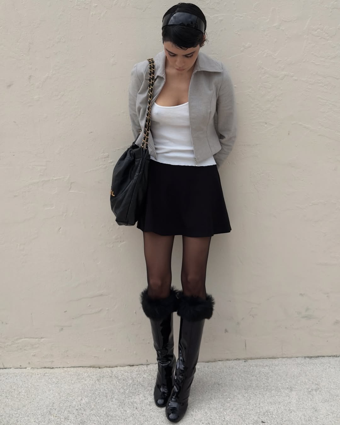 Mulher com tiara preta, minissaia, jaqueta curta e botas com pelúcia, em look inspirado na moda anos 60.