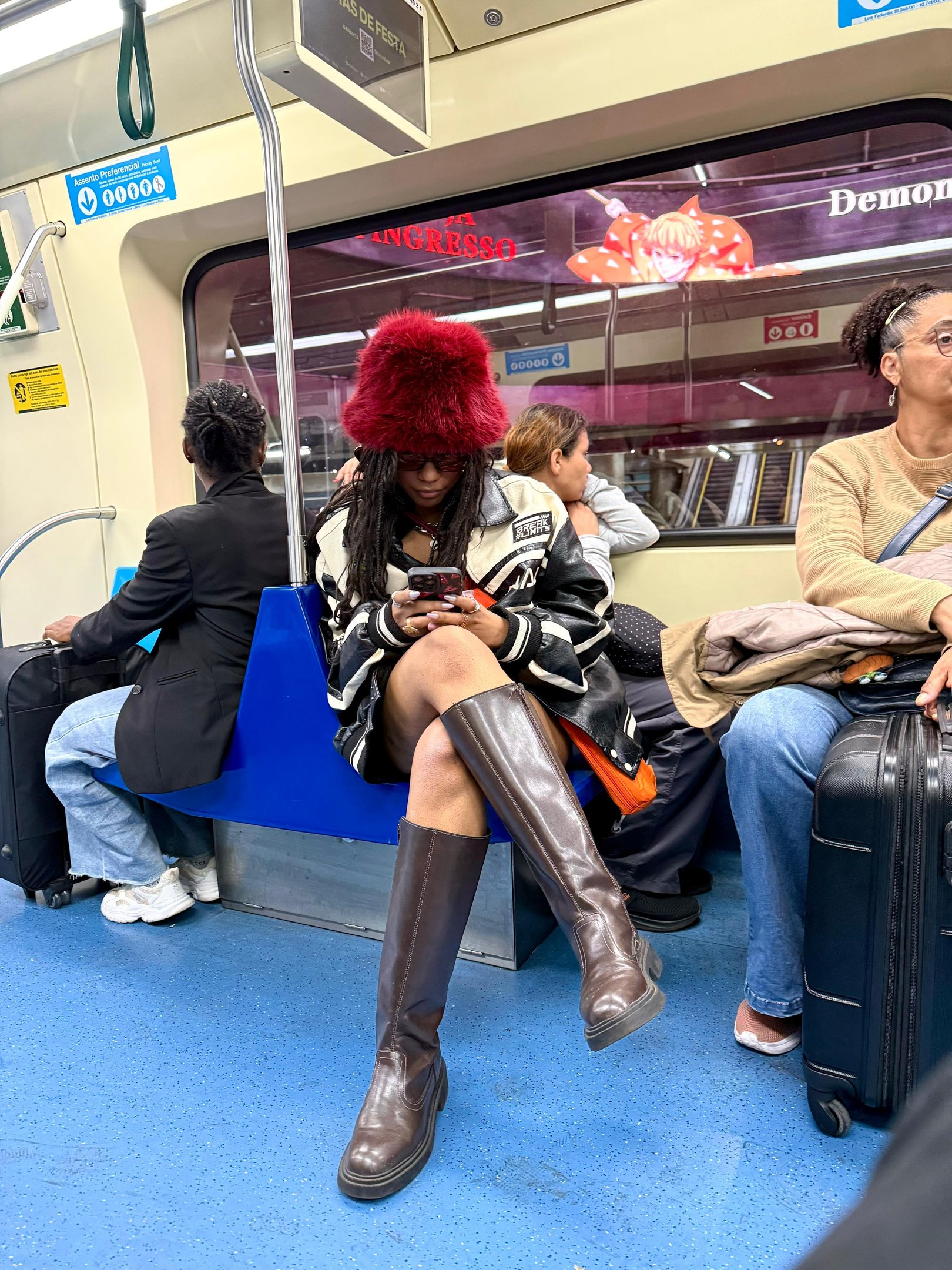 Passageiros em um metrô urbano, usando transporte público, com atenção aos celulares e bagagens ao redor.