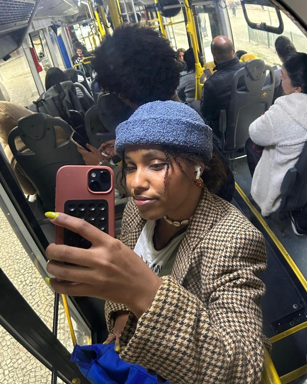 Pessoa tira selfie dentro de ônibus, mostrando interior movimentado do transporte público.