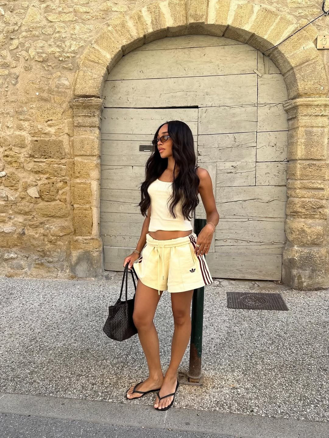 A imagem apresenta um look de verão com uma blusa cropped em tom claro, ideal para climas quentes. A combinação com shorts amarelos, que possuem detalhes em listras, traz um toque esportivo e descontraído. Modelos de blusa para verão