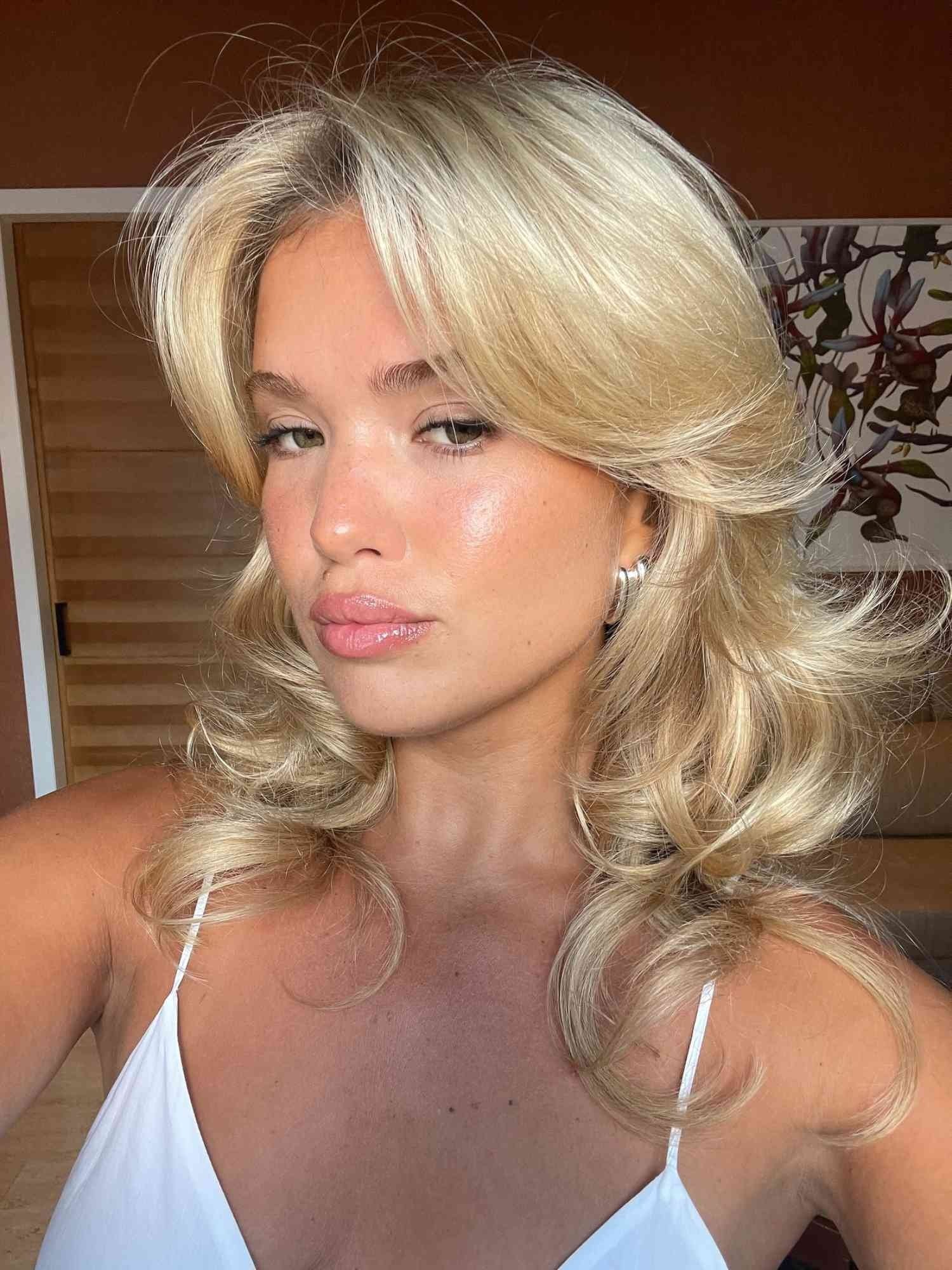 Cabelo loiro em camadas volumosas e longas, inspirando cortes de cabelo feminino como shag ou anos 70.
