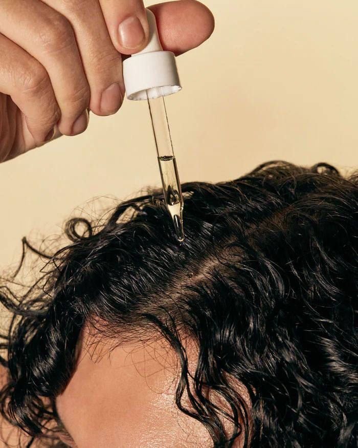 Aplicação de óleo no couro cabeludo com conta-gotas, destacando cuidados para hidratação e saúde capilar. Para que serve óleo de girassol