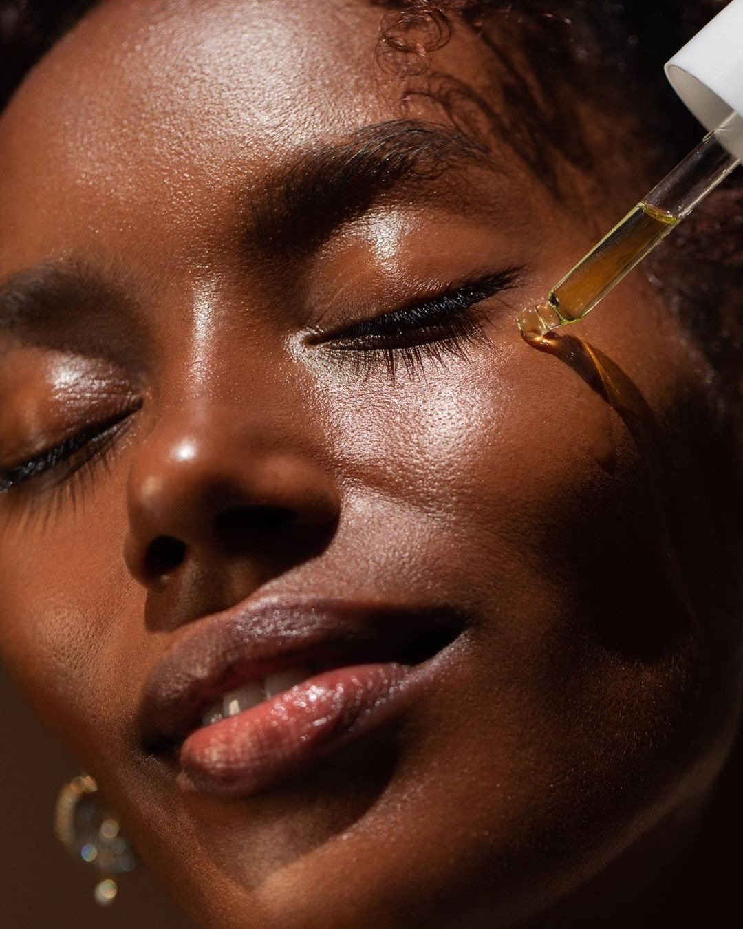 A imagem mostra uma mulher com pele radiante recebendo a aplicação de óleo. Para que serve óleo de semente de uva