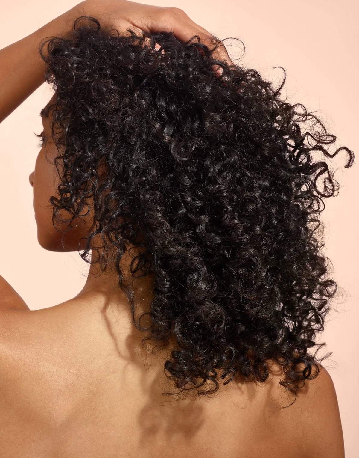 Cabelos cacheados e volumosos destacam-se na imagem, com um toque suave e brilhante. para que serve óleo de semente de uva