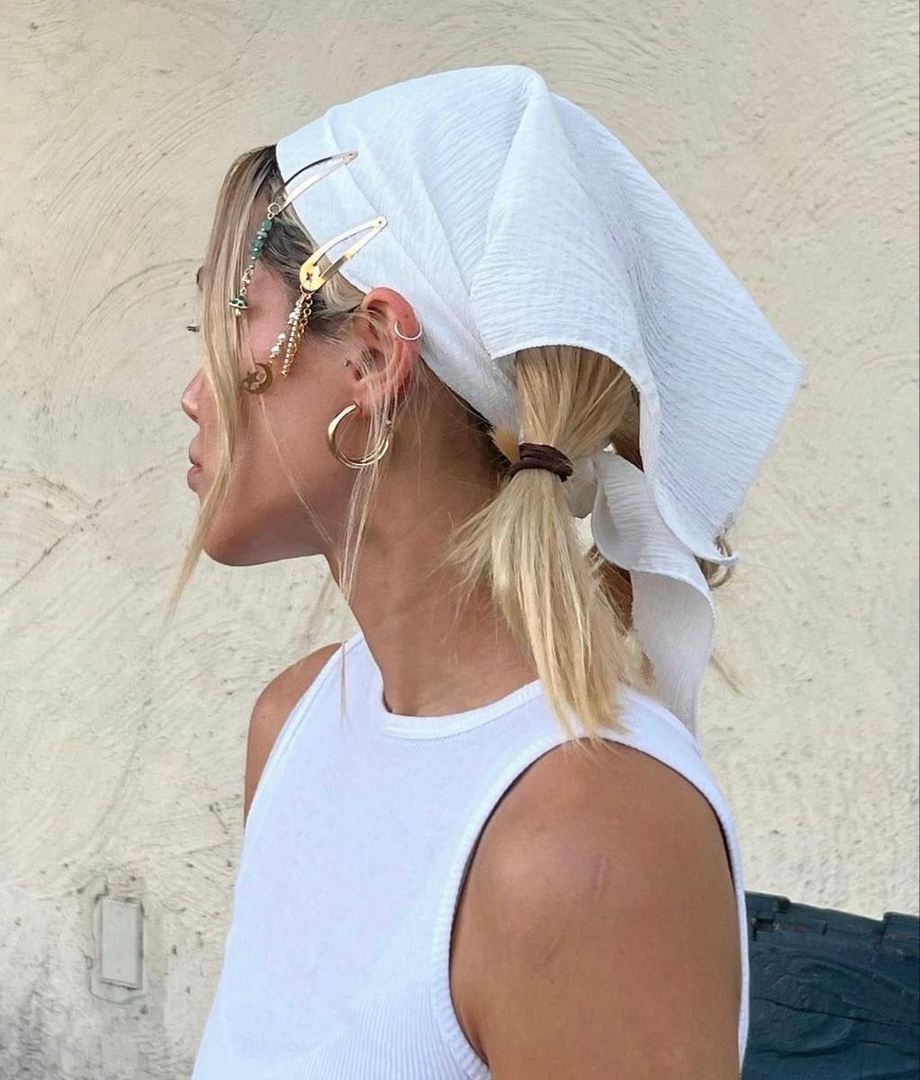 Mulher com bandana branca, cabelo preso com grampos e brincos grandes, ideal para penteados frescos no calor. Penteados para o calor