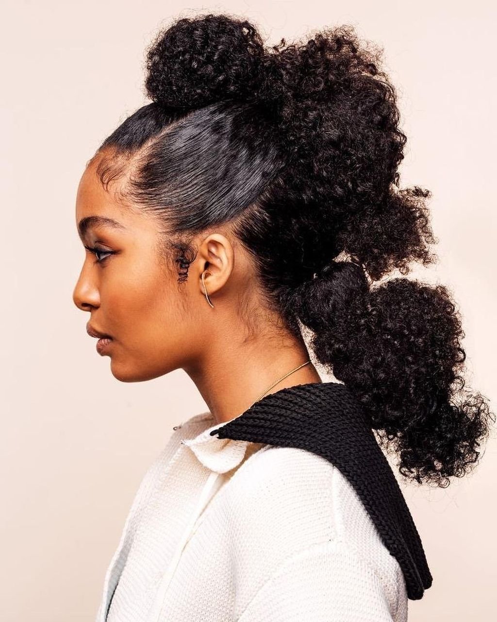 Jovem com penteado elegante de coques e cachos, ideal para dias quentes. Penteados para o calor