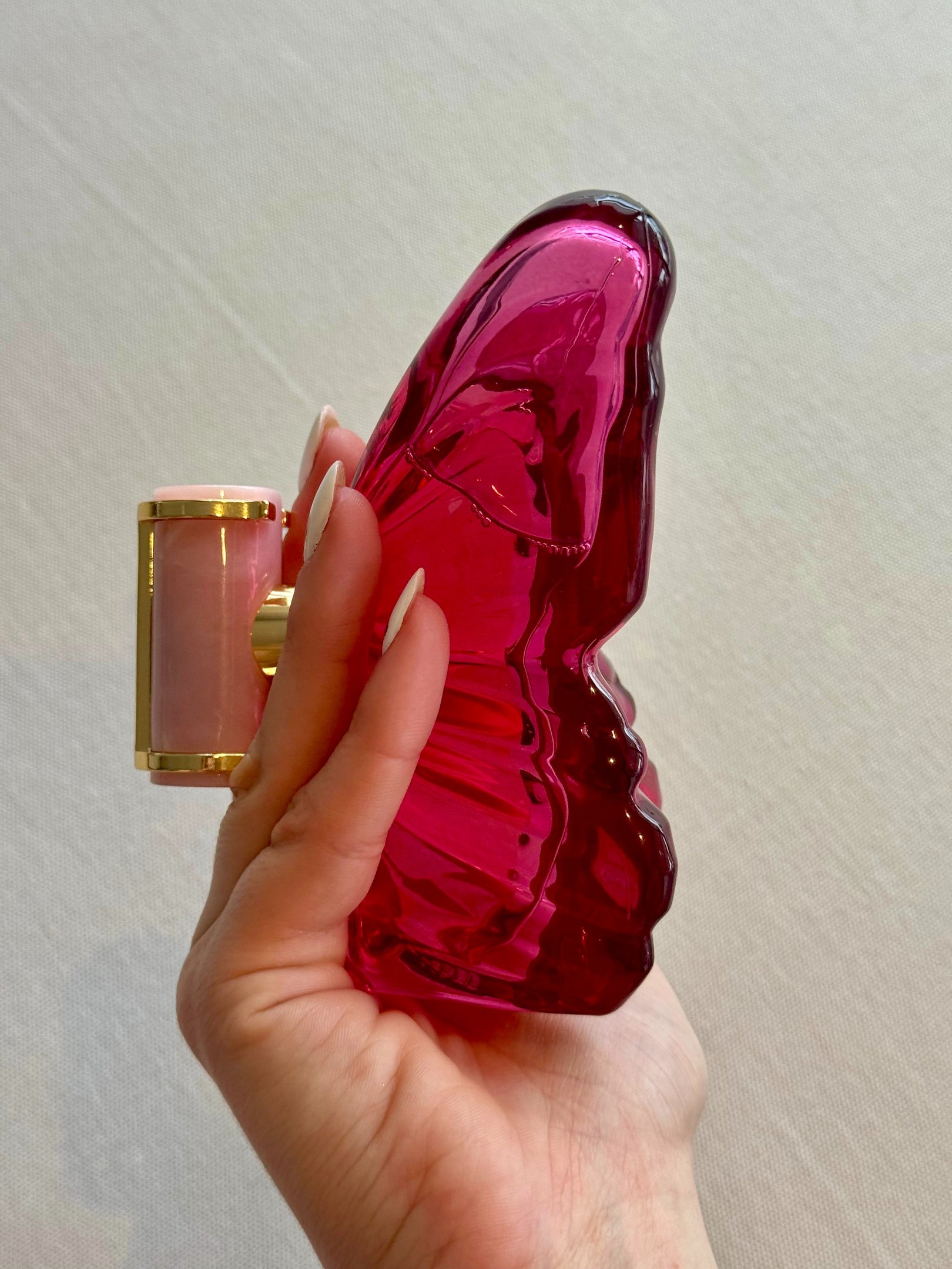 Frasco de perfume floral para primavera, com design moderno e elegante. A embalagem, em formato de borboleta, é predominantemente rosa e roxa, refletindo a leveza da estação. Ideal para quem busca frescor e sofisticação, esse perfume traz notas florais qu