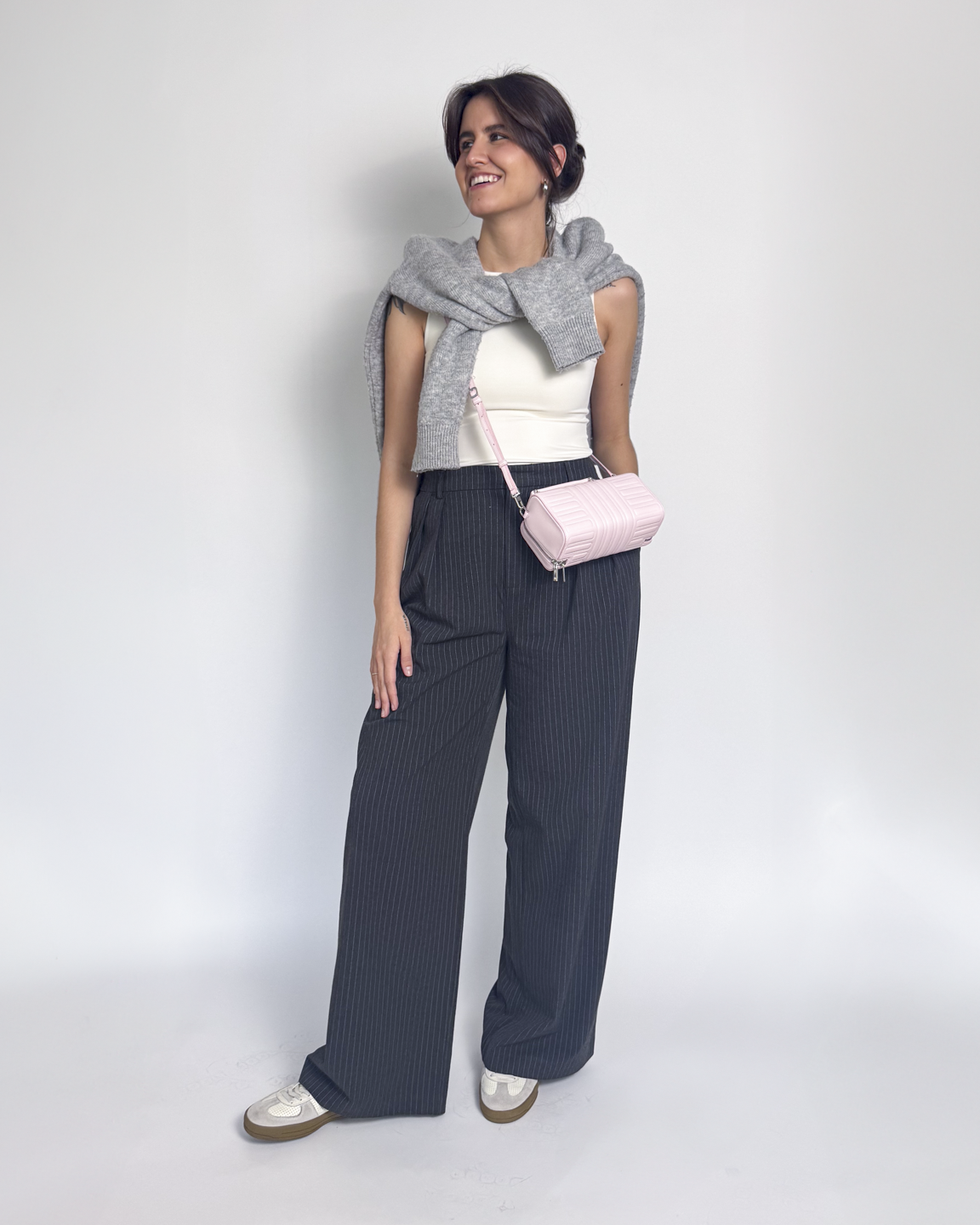 Mulher usa calça de alfaiataria, regata branca e cardigan, look de aeroporto estiloso