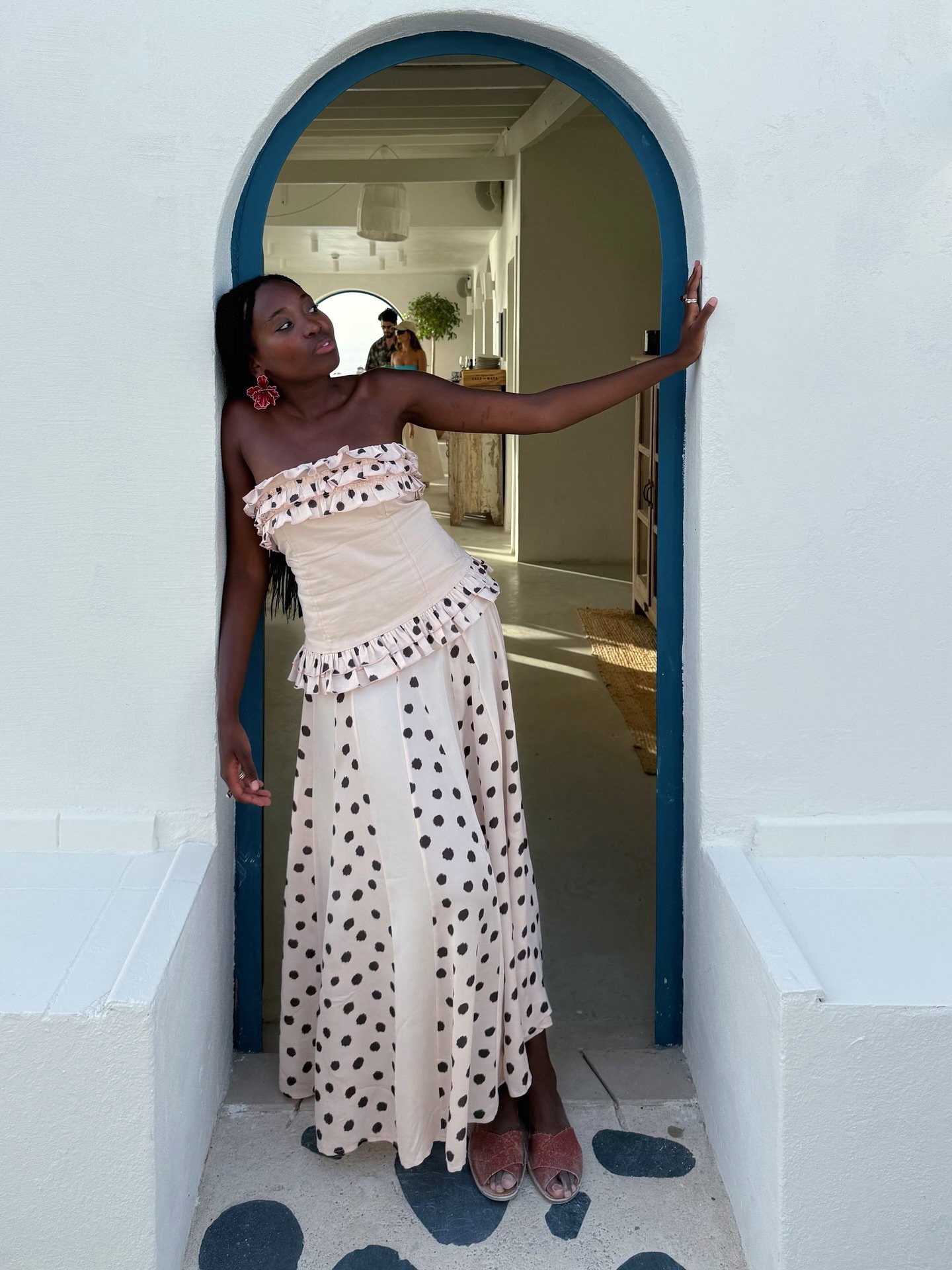 A mulher usa vestido com estampa de bolinhas e sandálias num arco usando sapato marrom