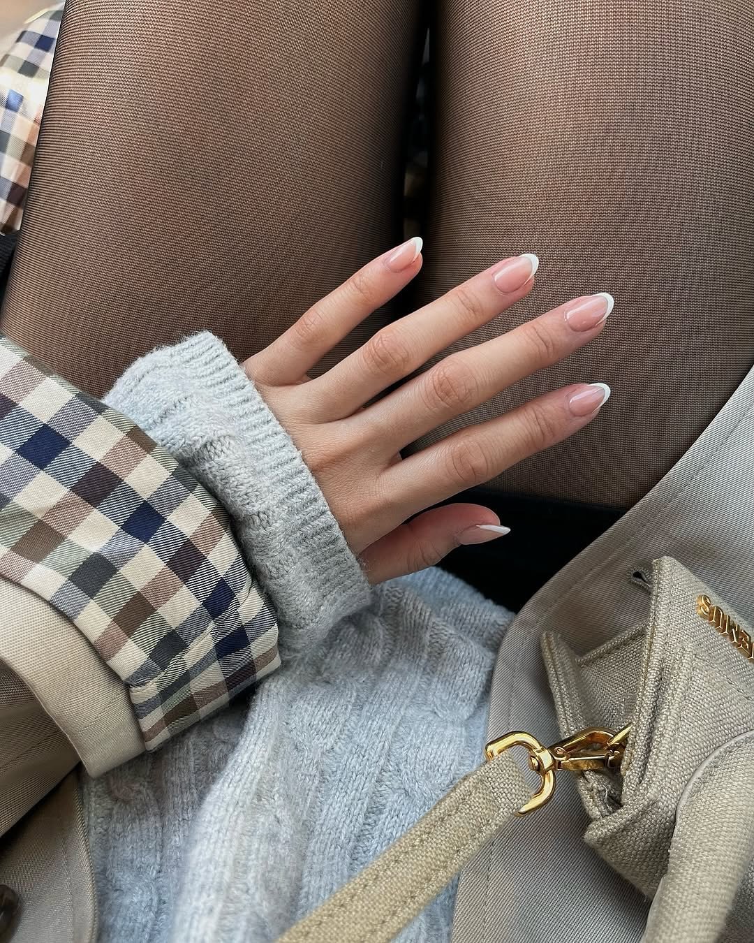 ideias de unhas nude com pontas brancas, estilo francês, sobre tecido xadrez e cinza.
