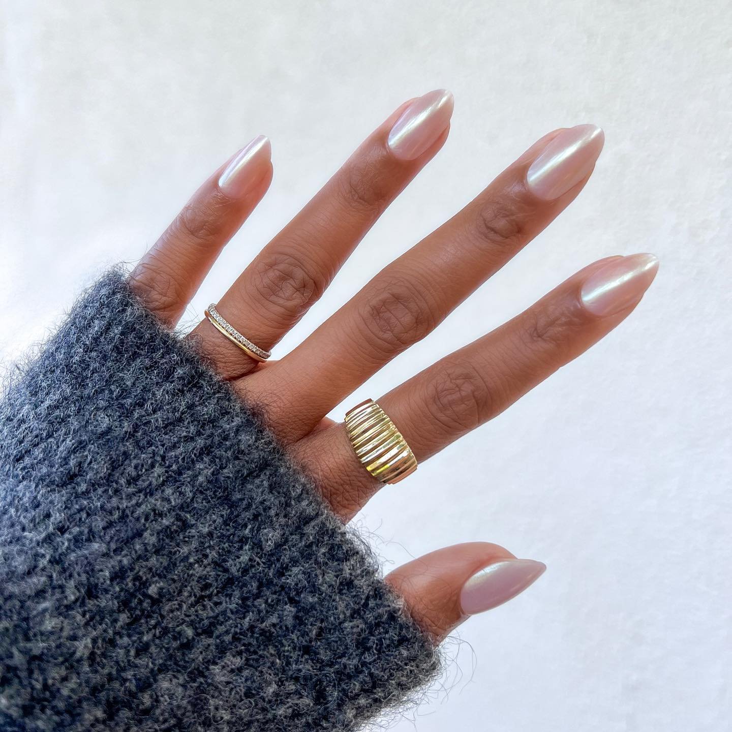 Unhas claras e delicadas pintadas de esmalte metálico perolado.
