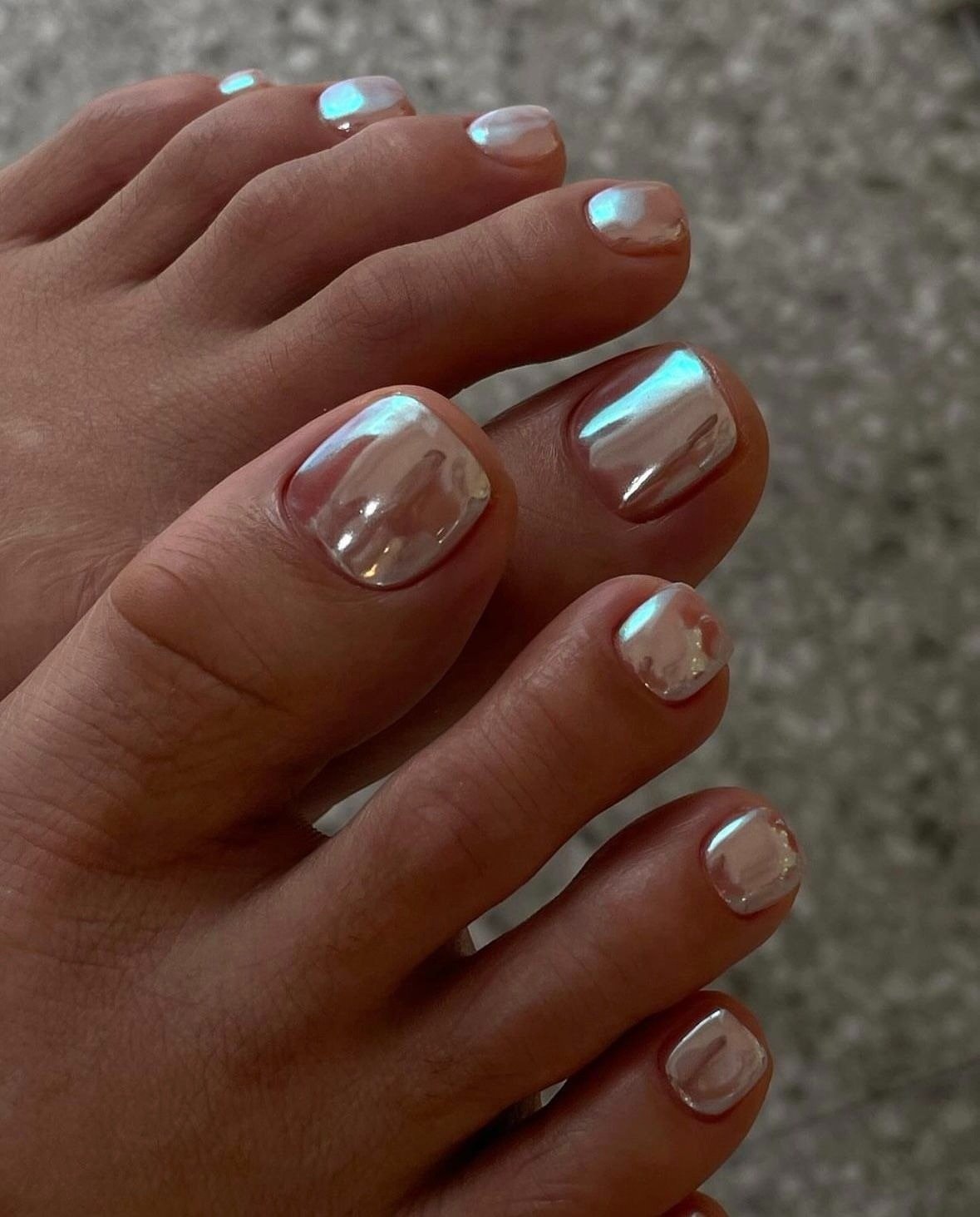 As unhas decoradas do pé apresentam um acabamento brilhante e sofisticado, com um tom perolado que reflete a luz, criando um efeito elegante. O design é clean e moderno, ideal para quem busca estilo e beleza. Essa tendência é perfeita para o verão, destac