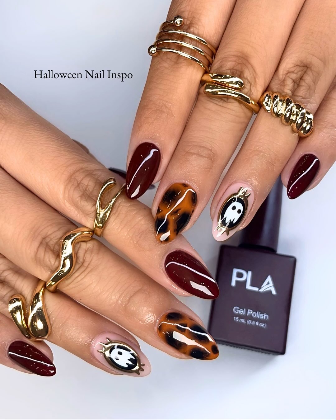 As unhas de Halloween exibem um design criativo e ousado, combinando tons de vinho e marrom com detalhes temáticos.