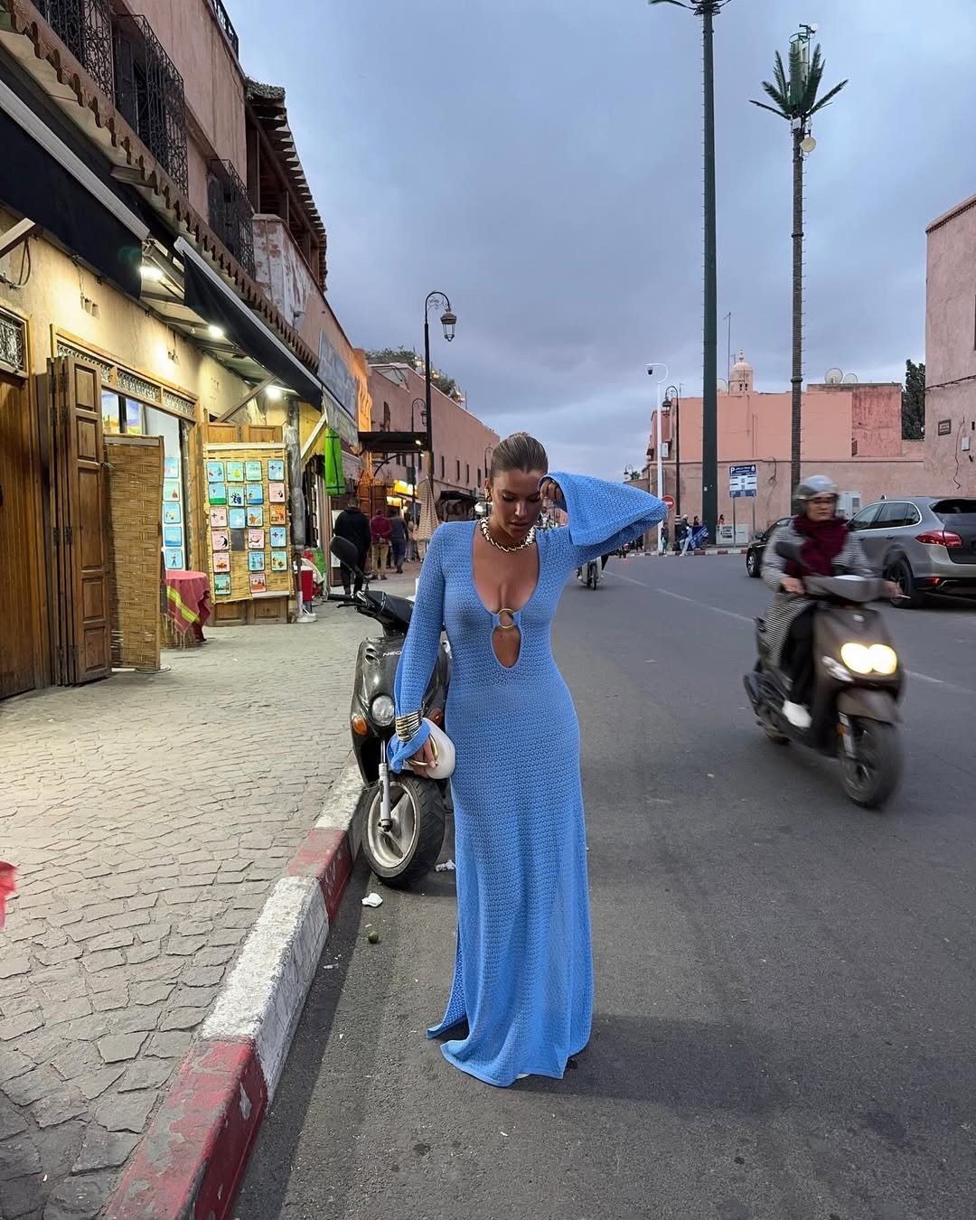 Um vestido saída de praia em tom azul vibrante destaca-se na imagem, apresentando um design longo e justo, com um decote ousado e detalhes em crochê.