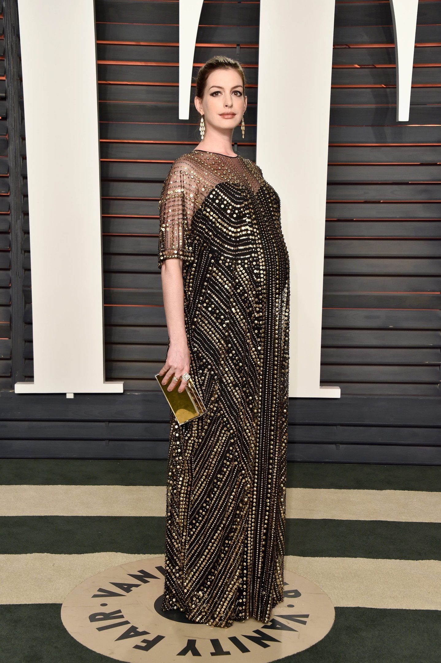 Anne Hathaway exibe estilo elegante com vestido longo preto e dourado bordado, modelagem fluida e transparência delicada,