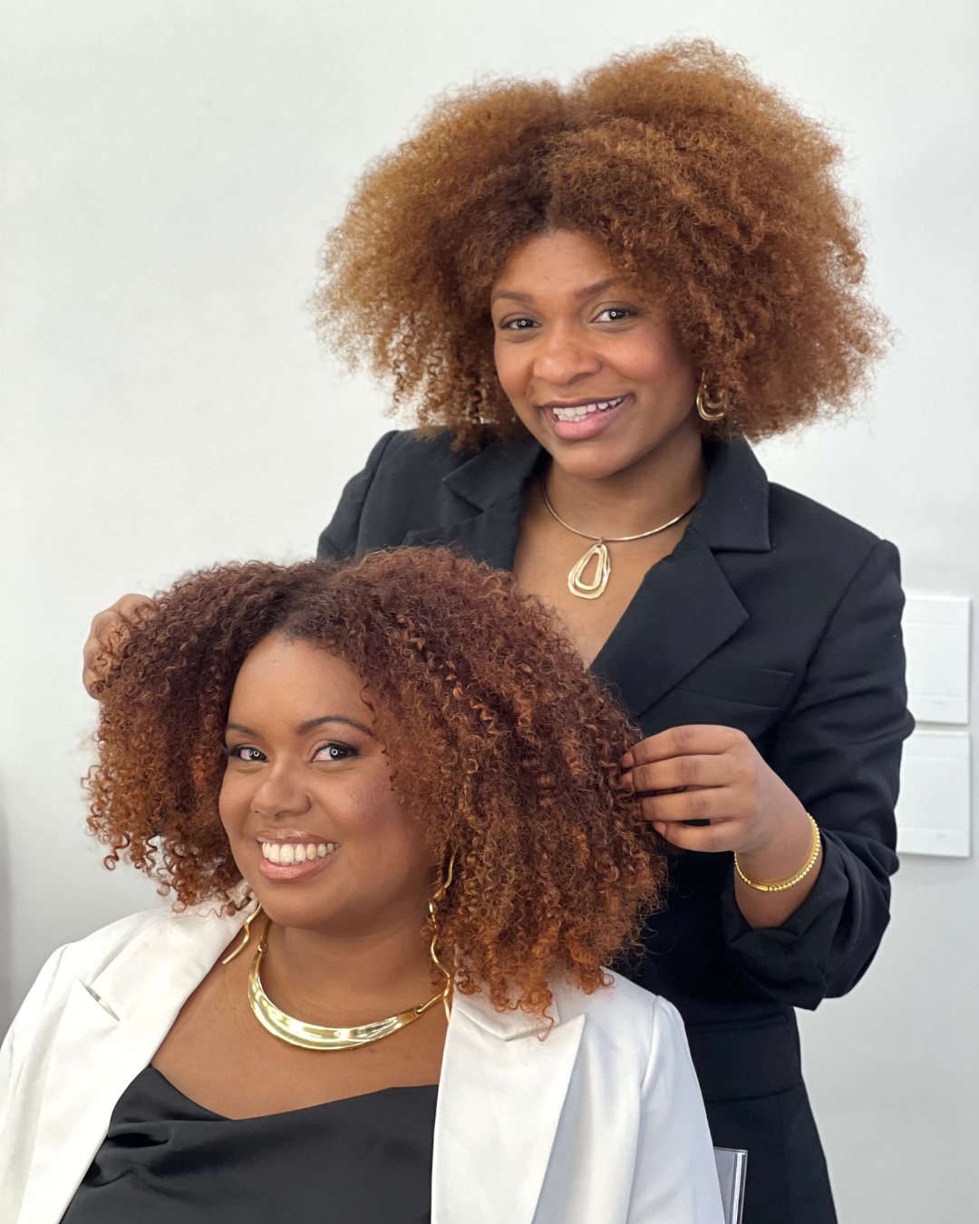 Modelo sorridente segura produto L\'Oréal Inoa para coloração de cabelos crespos e cacheados, com profissional da marca. 