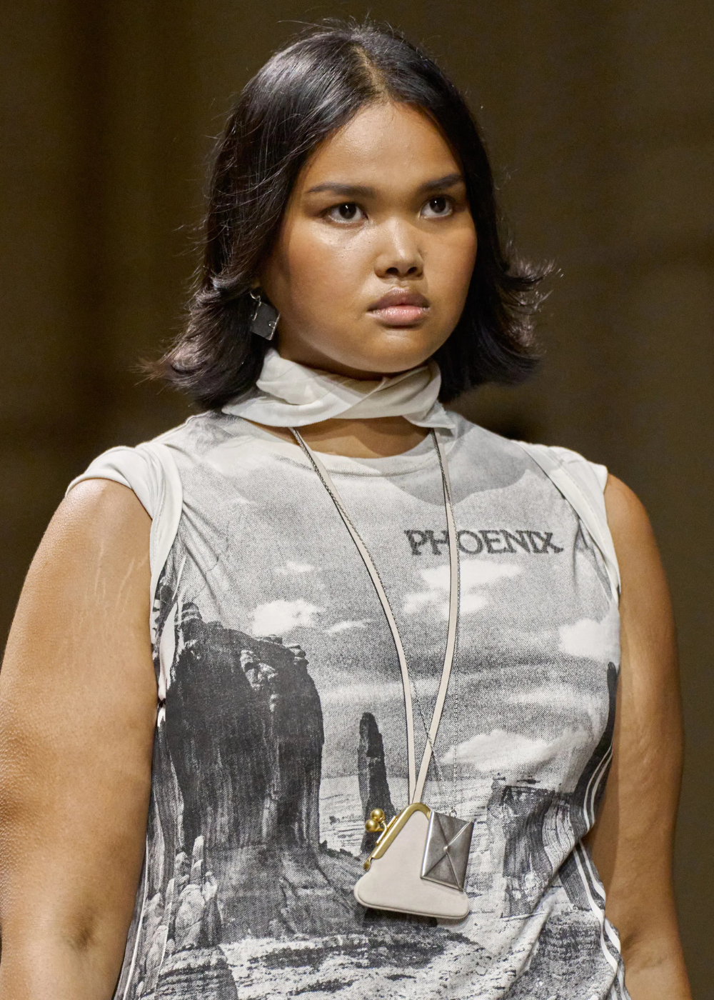 Mulher na passarela da coach usando maxi colar funcional prata.