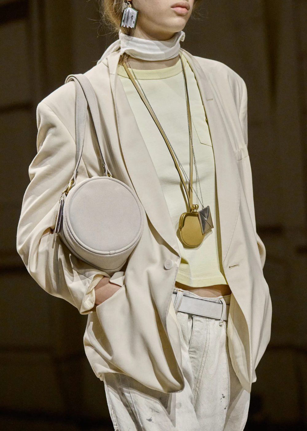 Pessoa na passarela da Coach usando colar funcional dourado.