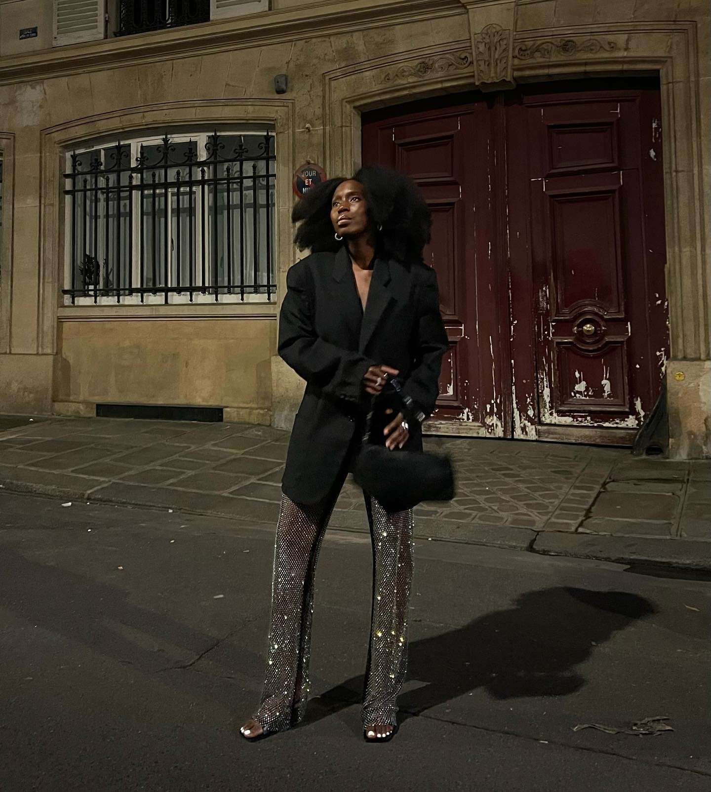 Modelo posa à noite com blazer oversized preto e calça reta de paetê prateado, combinando elegância e brilho para 2026.