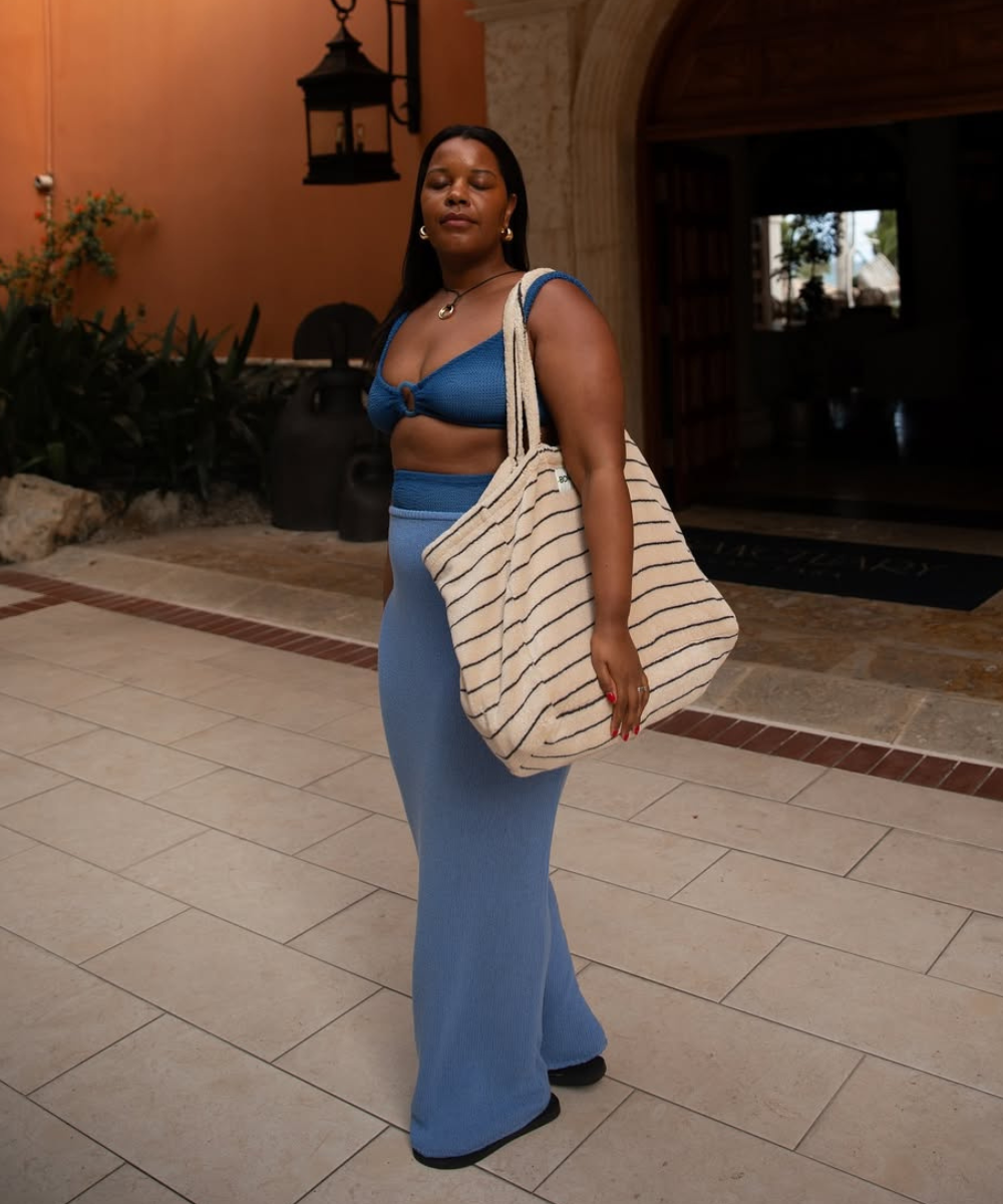 Como usar saída de praia com saia longa azul de malha e top de crochê combinando, bolsa listrada e postura confiante para