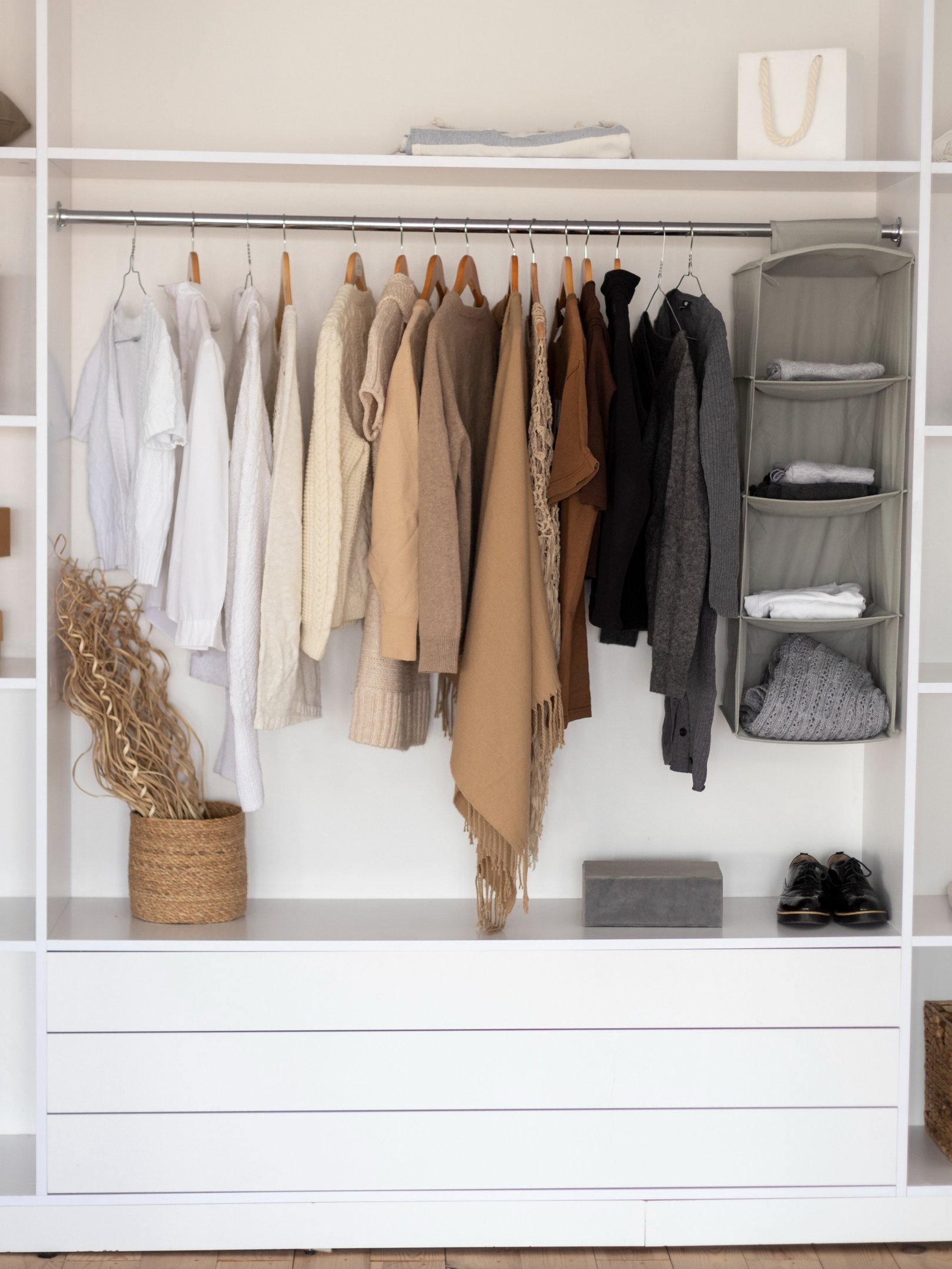 Closet pequeno com organização minimalista, peças em tricô e algodão nas cores neutras bege, branco e cinza, ambiente