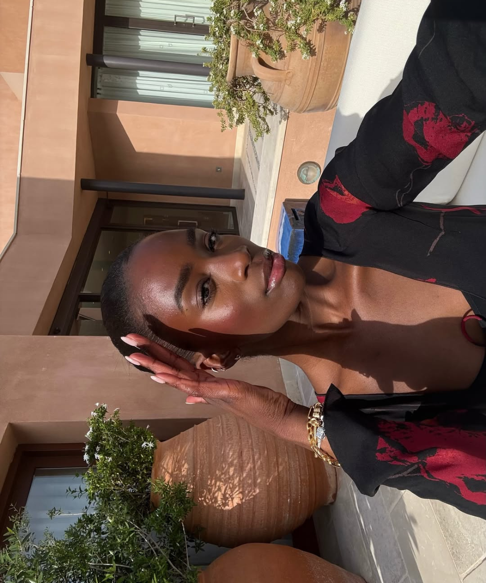 Modelo posa sob luz natural com blusa preta de tecido leve e estampa vermelha, destacando pele radiante e dicas para ter uma