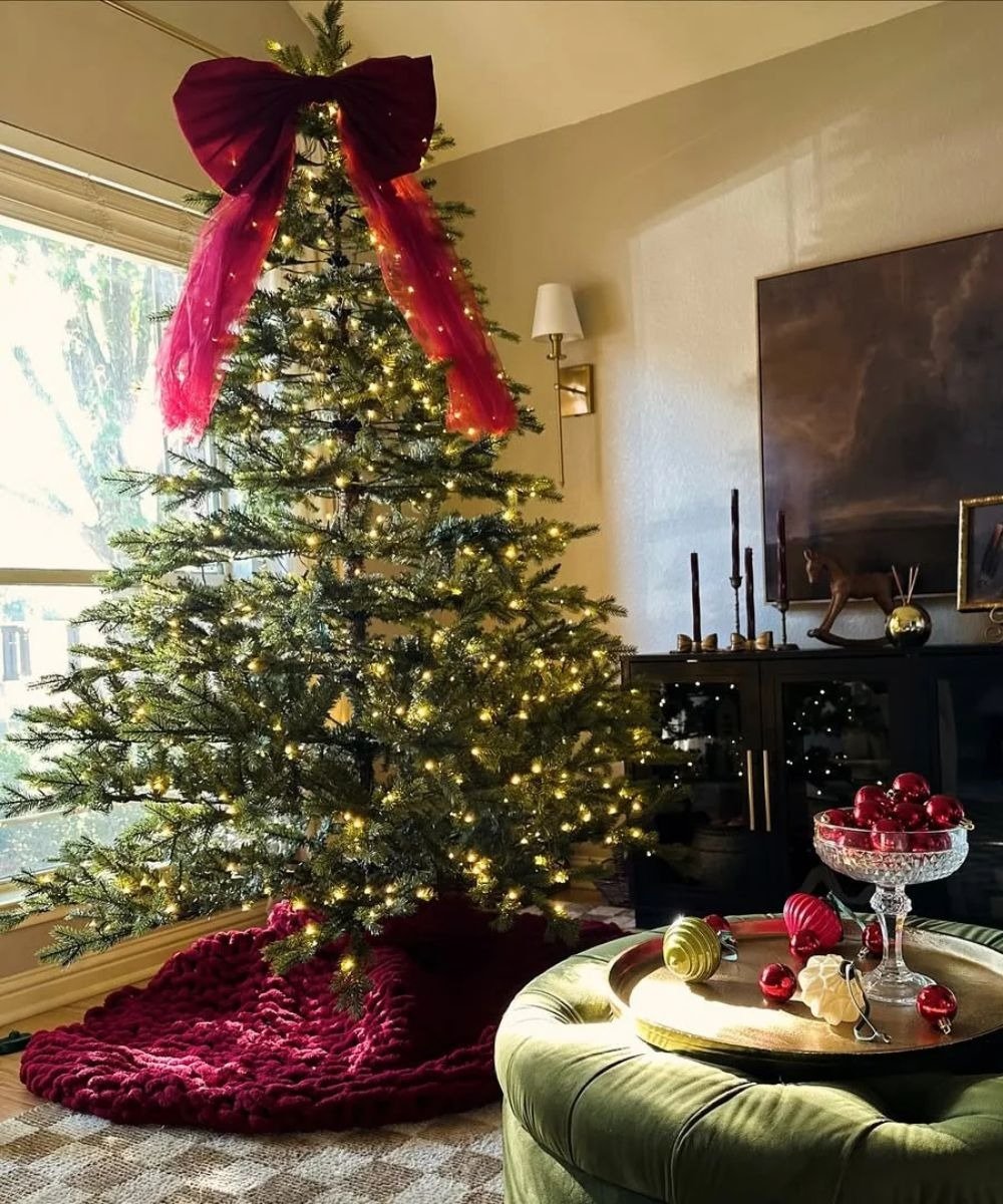 Árvore de Natal natural com luzes brancas, laço e saia de tricô vinho. Uma das melhores ideias de árvore de Natal