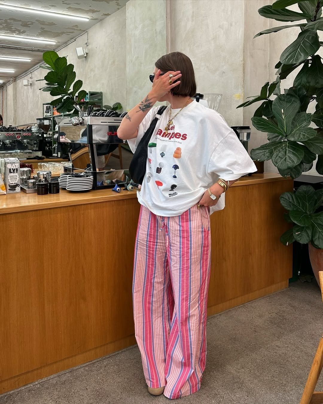 Look rosa com calça listrada ampla em tons de rosa e branco combinada a camiseta branca oversized com estampa colorida.