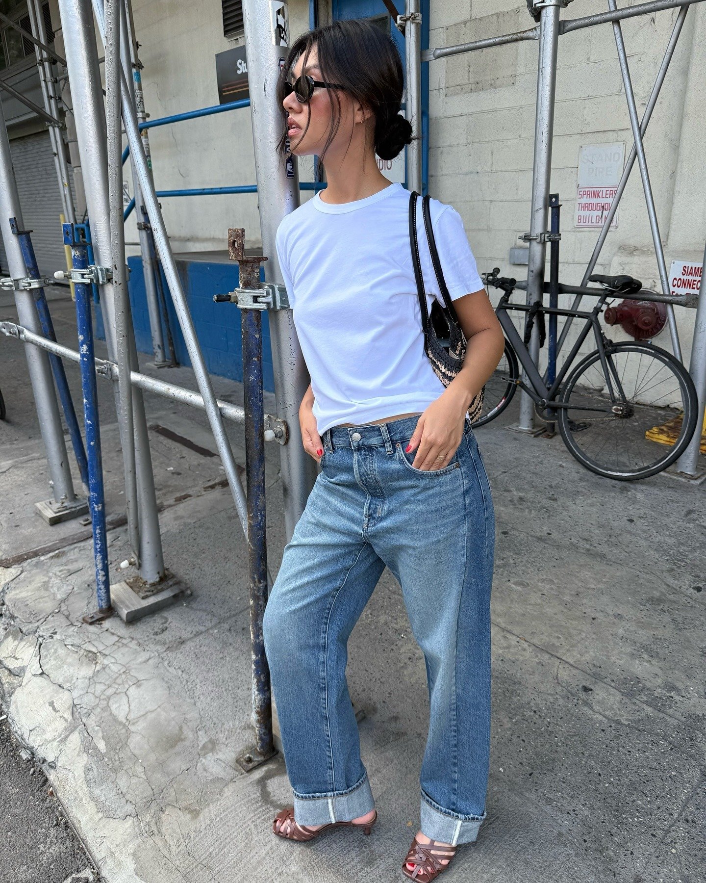 Este look t-shirt apresenta uma camiseta branca básica, ideal para compor um visual casual e moderno. A combinação com jeans de corte amplo e despojado traz conforto e estilo, enquanto as sandálias de salto adicionam um toque sofisticado.