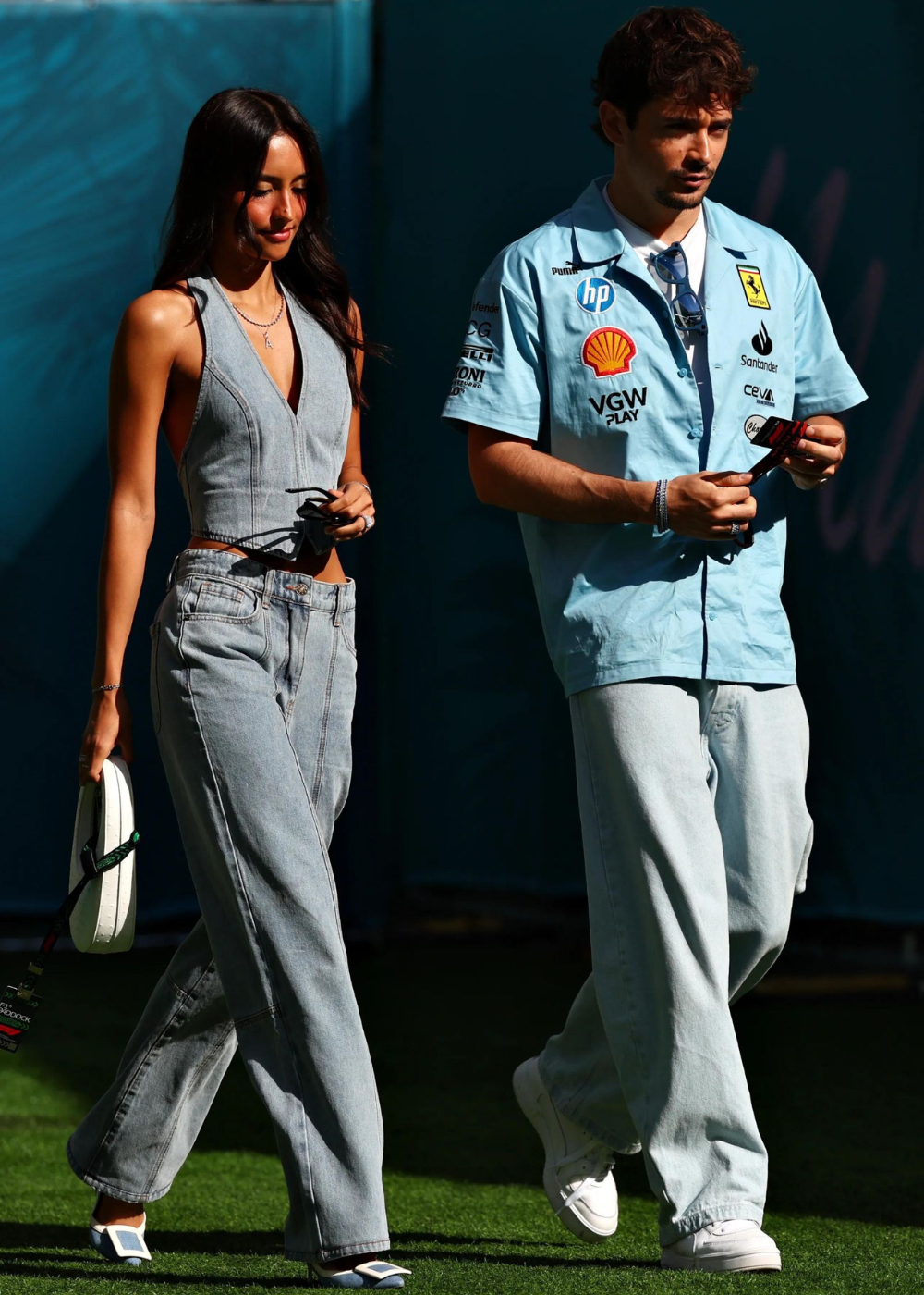 Alexandra Saint Mleux exibe um look moderno e despojado, combinando um top cropped em jeans com calças largas da mesma tonalidade. Os detalhes de sua roupa destacam a silhueta, enquanto os sapatos brancos adicionam um toque de elegância.