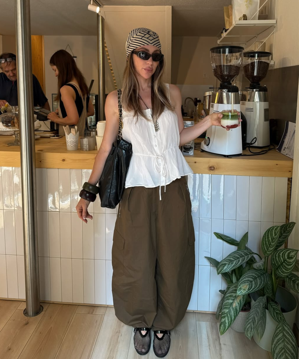 Look com calça balonê marrom em tecido estruturado, blusa branca leve, acessórios oversized e estilo urbano descontraído.