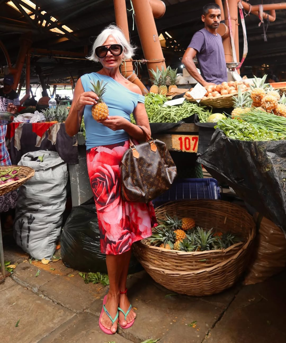 Look com saia vermelha floral midi em tecido leve combina blusa azul ombro a ombro e chinelos coloridos, modelo segura