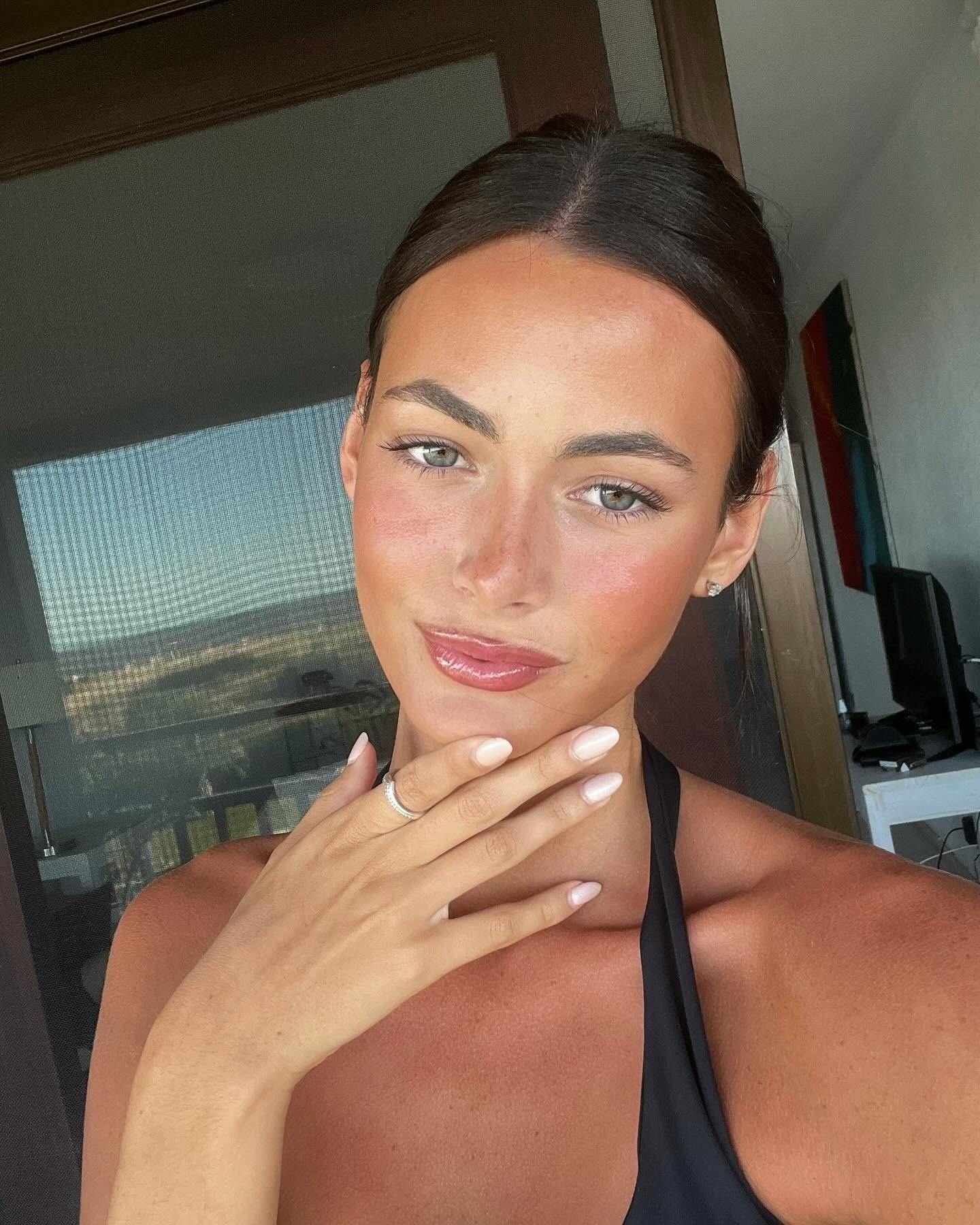 Modelo com maquiagem para praia leve e natural realça pele bronzeada, com blush rosado, gloss labial e sobrancelhas