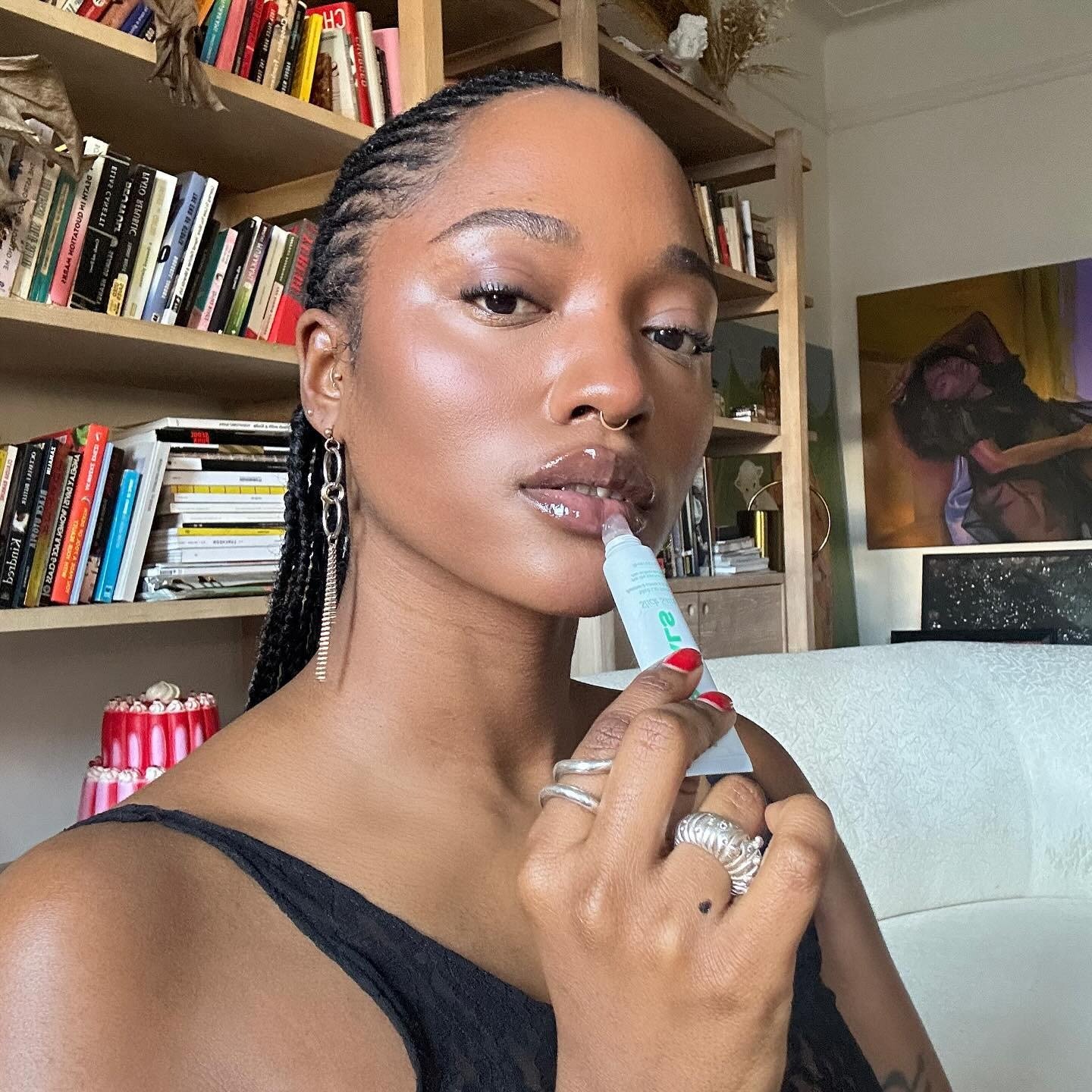 A imagem apresenta uma mulher aplicando um hidratante labial em um ambiente acolhedor. Melhores hidratantes labiais