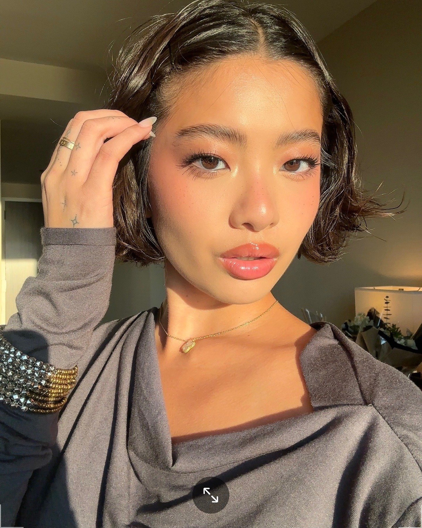 A imagem mostra uma mulher com cabelo curto e ondulado, destacando lábios bem hidratados e brilhantes.