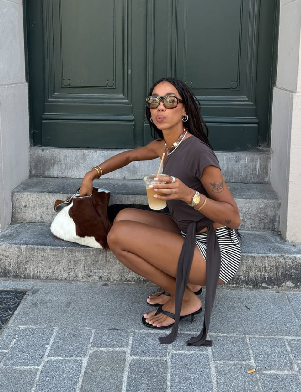 O look com micro shorts destaca-se pela combinação de conforto e estilo. A modelo usa uma blusa de manga curta em tom neutro, complementada por micro shorts listrados, que valorizam a silhueta.