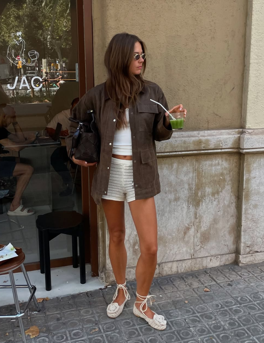Neste look com micro shorts, a modelo exibe um estilo casual e sofisticado. Ela combina shorts brancos de crochê com uma blusa cropped branca, criando uma silhueta leve e fresca.