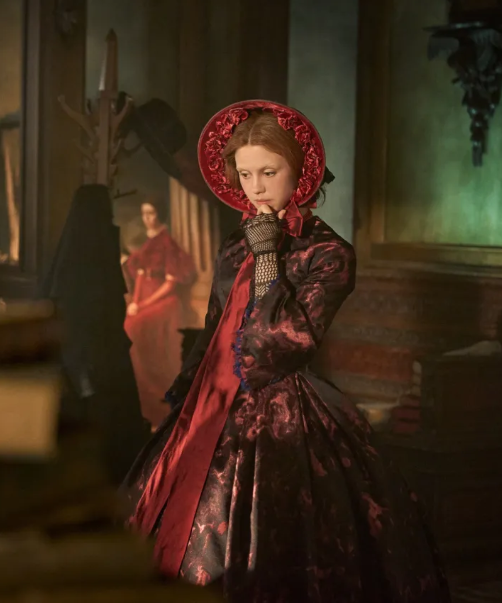 Figurino de Frankenstein com vestido vitoriano em tecido brocado preto e vermelho, chapéu de abas largas e luvas rendadas,