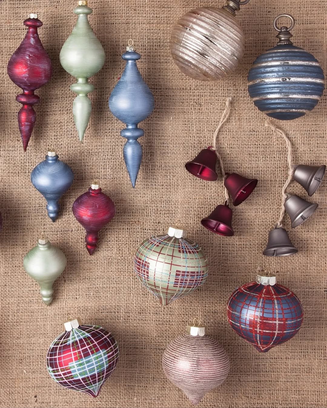 Enfeites para árvore de Natal com bolas e sinos em tons metalizados de vermelho, azul, verde e dourado.