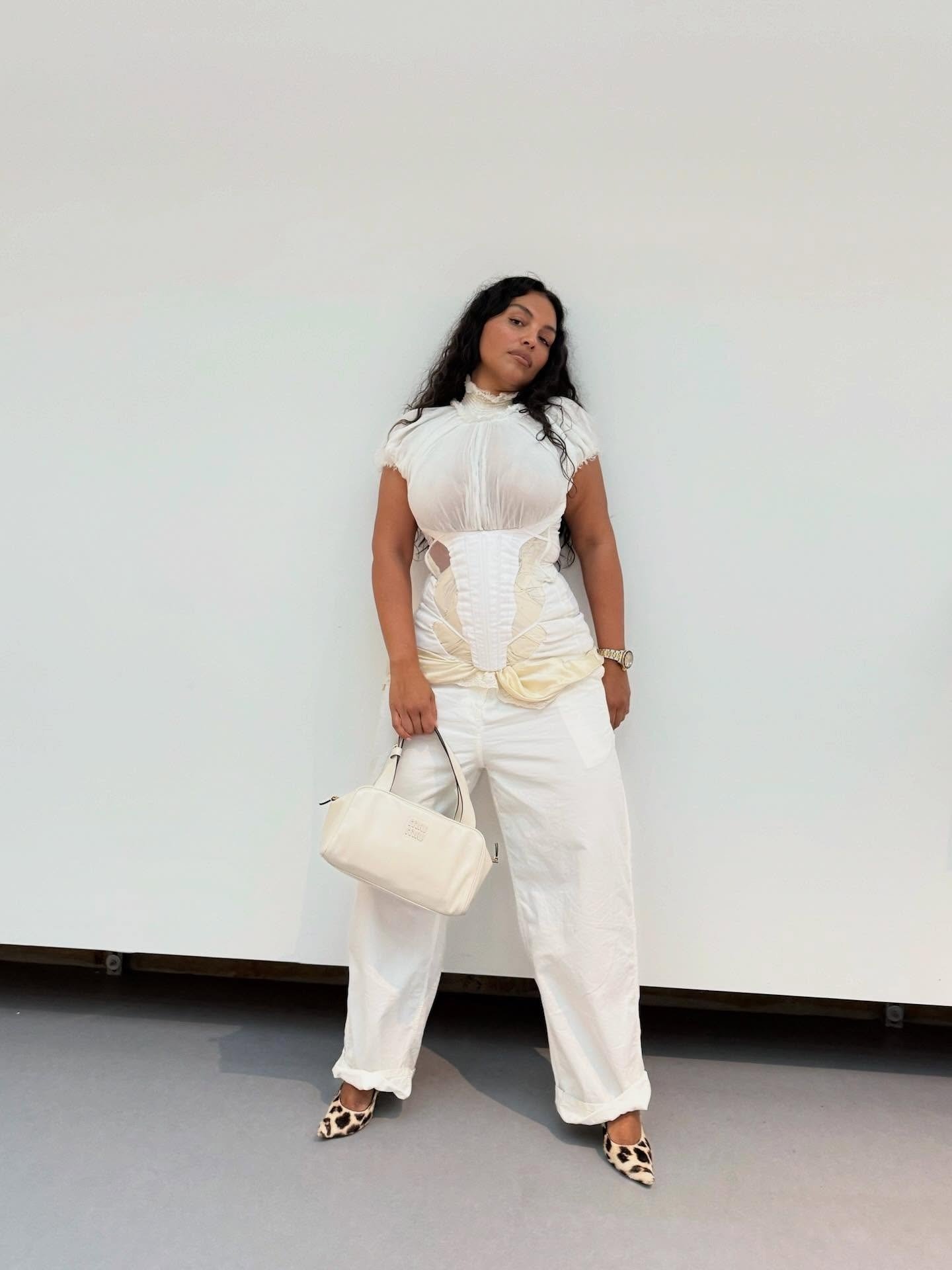 Paloma Elsesser posa com elegância em blusa branca de tecido leve com corpete estruturado, calça ampla off-white e scarpin.