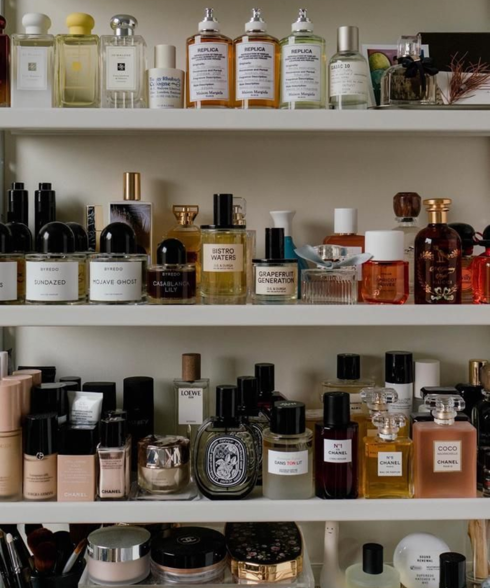 Prateleiras organizadas com perfumes de vidro transparente e âmbar, rótulos minimalistas em preto e branco, sugerindo