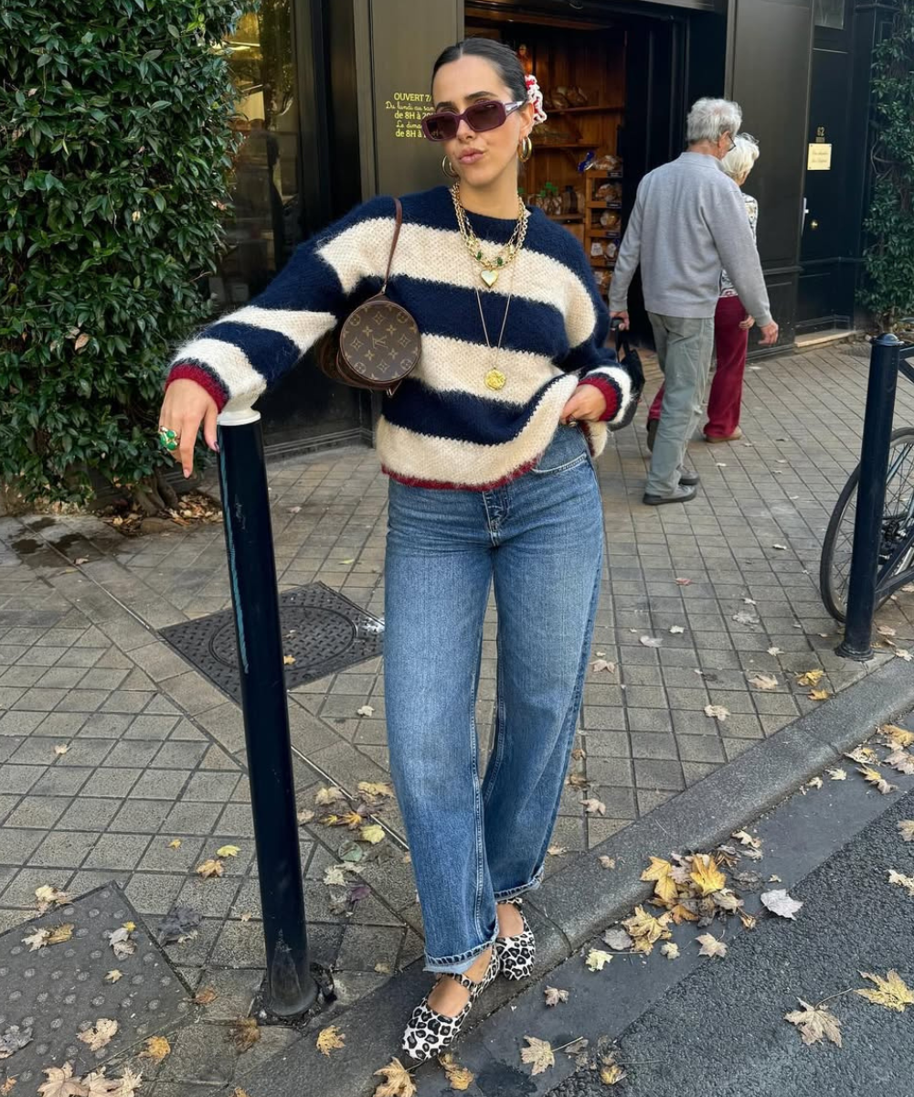 Modelo posa com suéter listrado azul e branco, jeans reto e sapatos estampados tendência em animal print, estilo casual