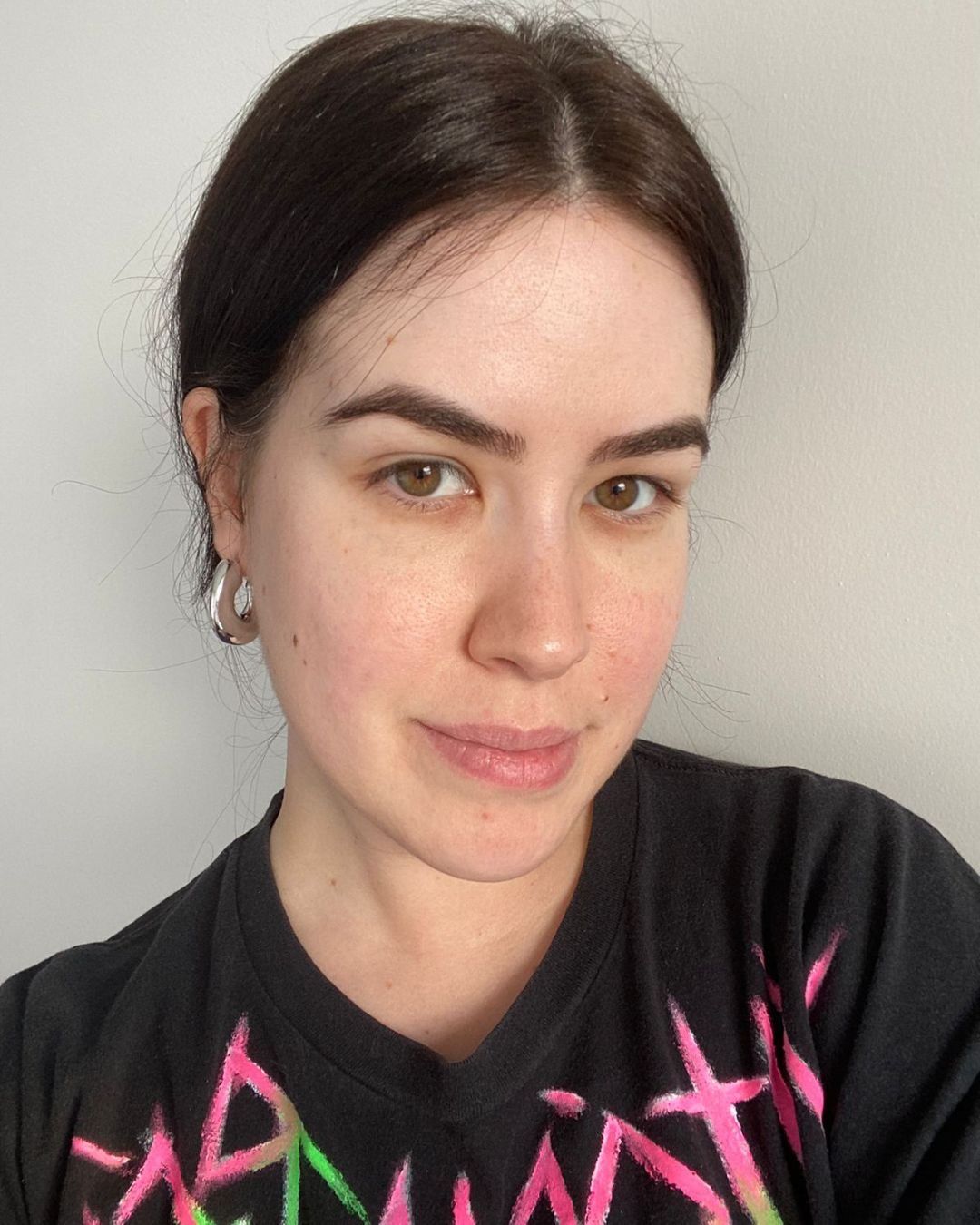 Rosto limpo e natural, destacando a pele saudável e bem cuidada. O uso de sérum facial pode ser percebido na luminosidade e