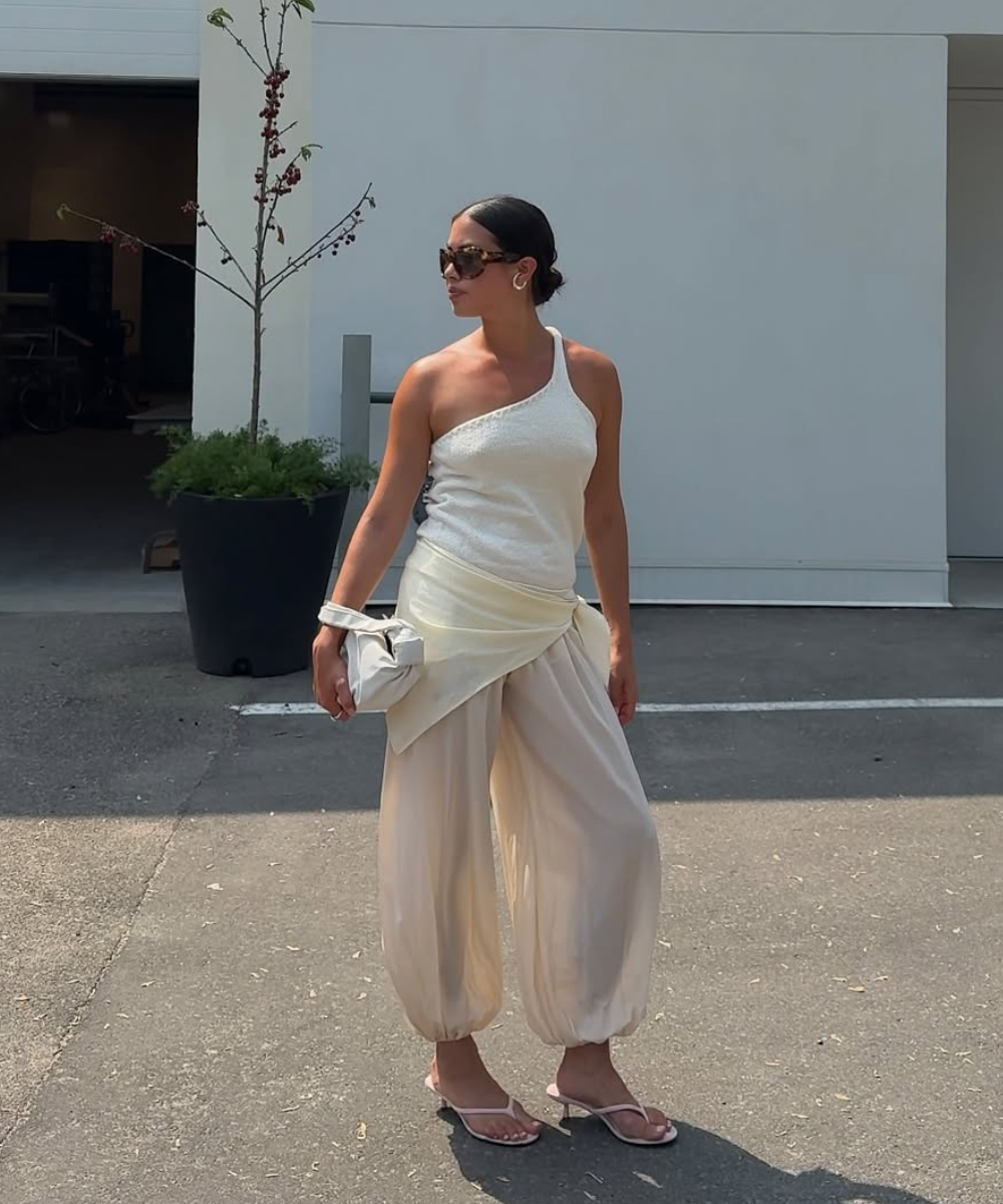 Modelo posa com regata assimétrica de tricô e calça ampla de tecido leve em tons neutros, transmitindo elegância e conforto