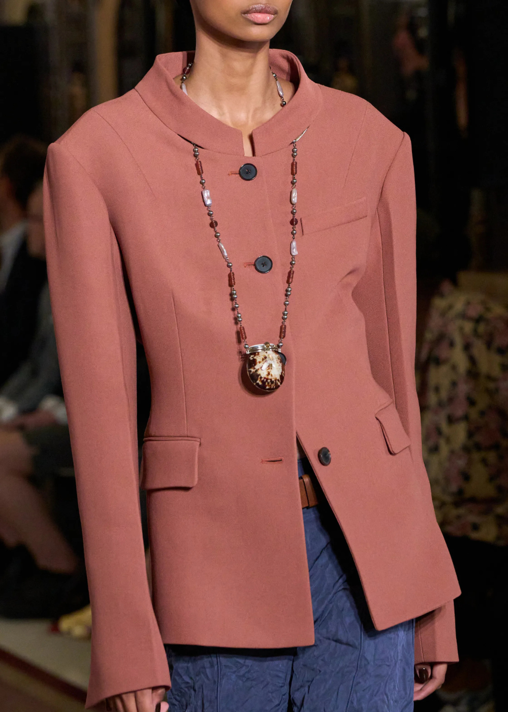 Mulher desfilando com colar funcional de Tory Burch.