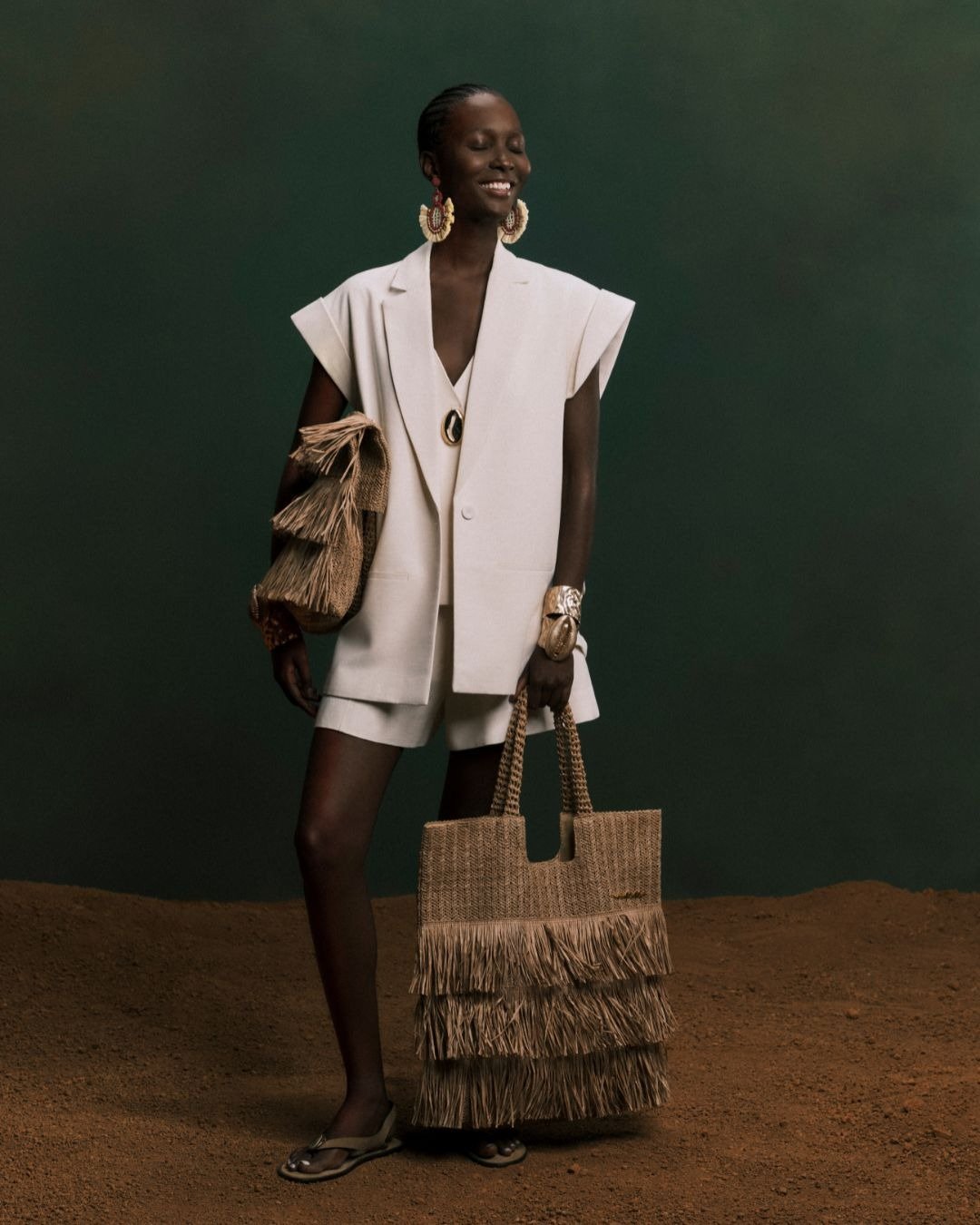 Modelo vestindo um conjunto leve e arejado, com blazer oversized e short, complementado por acessórios de palha. A imagem sugere elegância e frescor, ideal para combinar com tricô no verão.