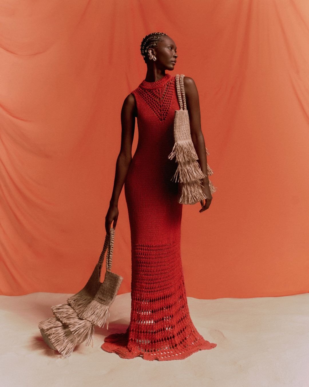 Vestido de tricô no verão vermelho com detalhes vazados. Acompanhado por bolsa com franjas, combina estilo e frescor.