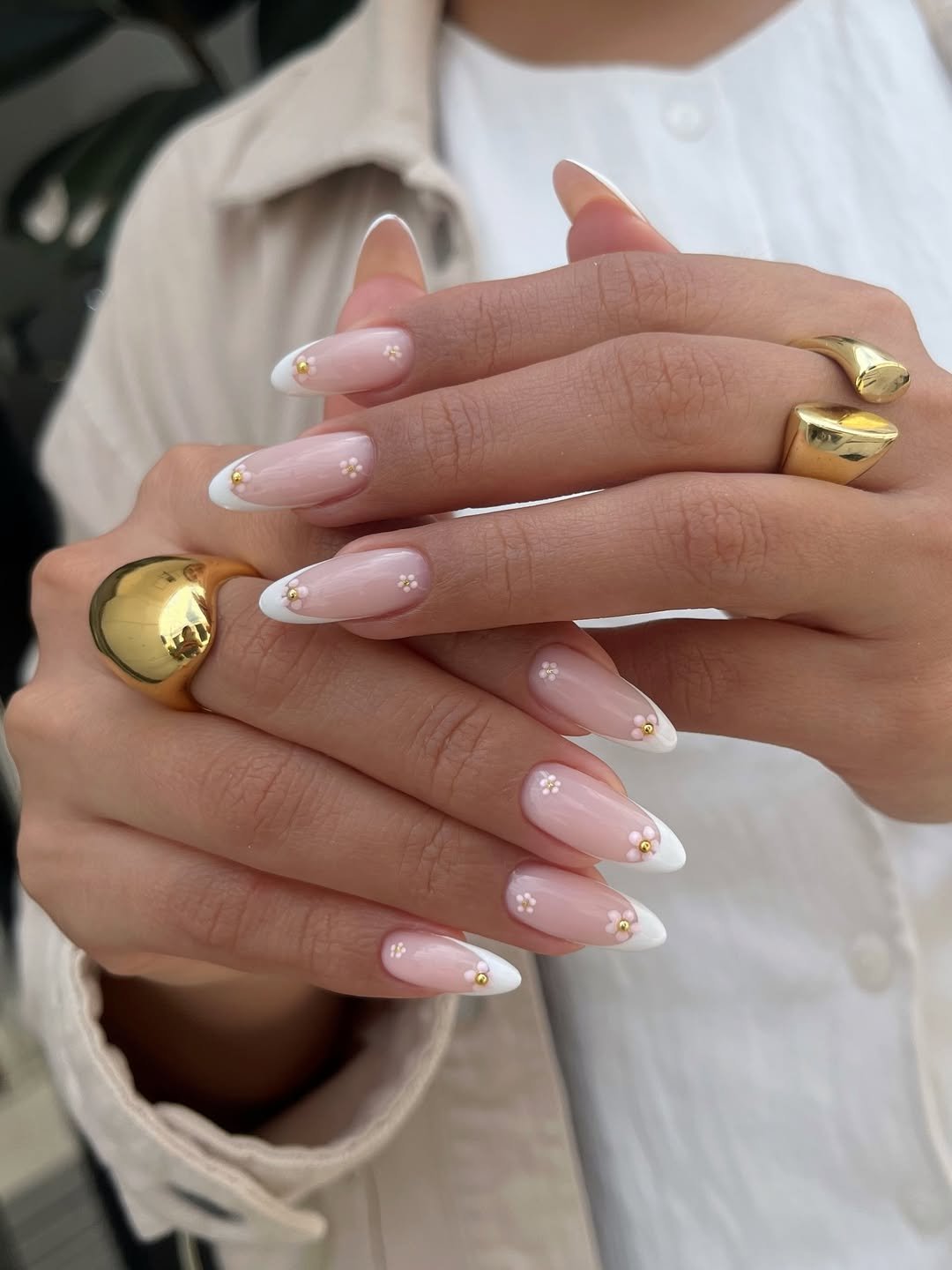 Unhas para o natal e ano novo com francesinha branca delicada e mini flores 3D douradas em base rosada.